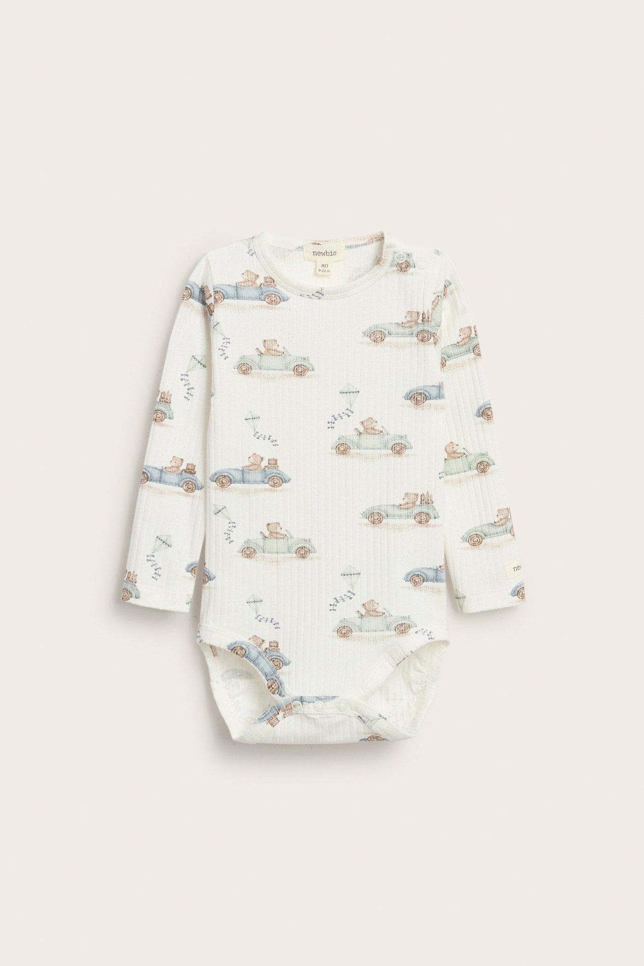 Offwhite long-sleeved ribbed body with car print, snap buttons on shoulder and crotch.