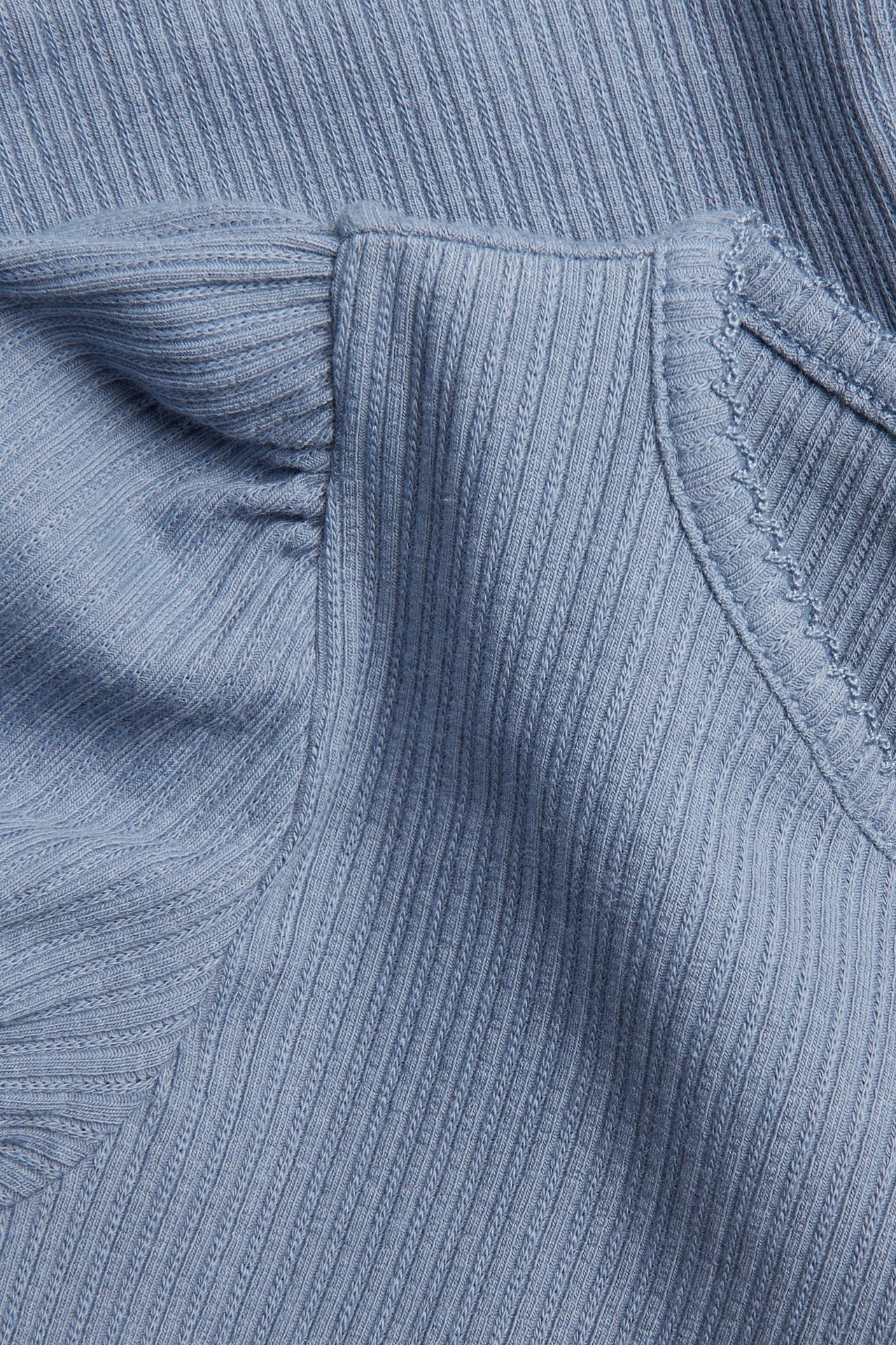 Nahaufnahme eines hellblauen gerippten Jersey-Oberteils mit kurzen Puffärmeln und Picotrand.