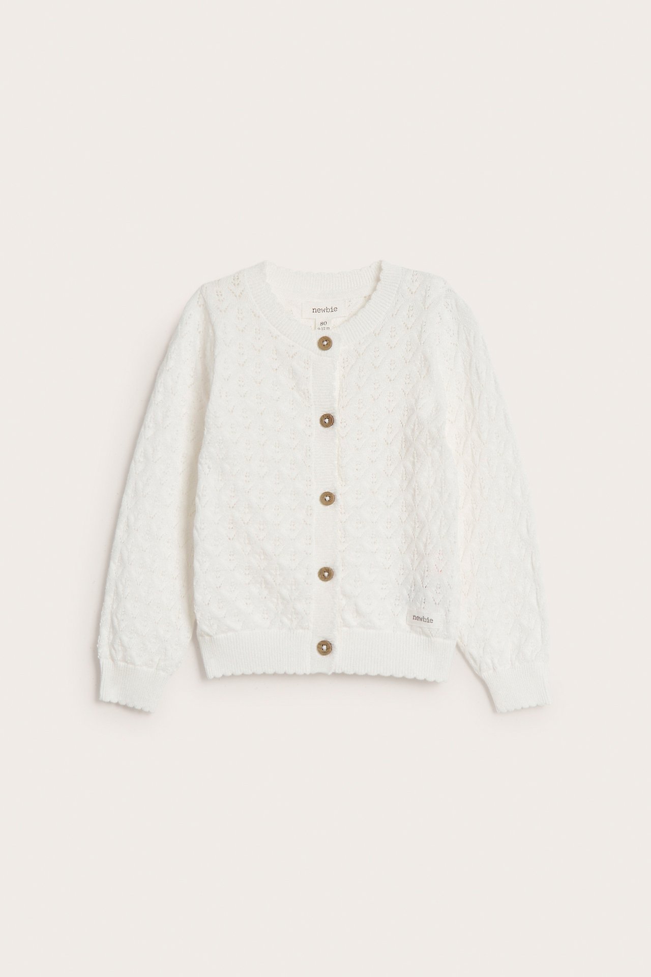 Front view of an off-white patterned knitted cotton cardigan with a scalloped hem and wooden buttons.