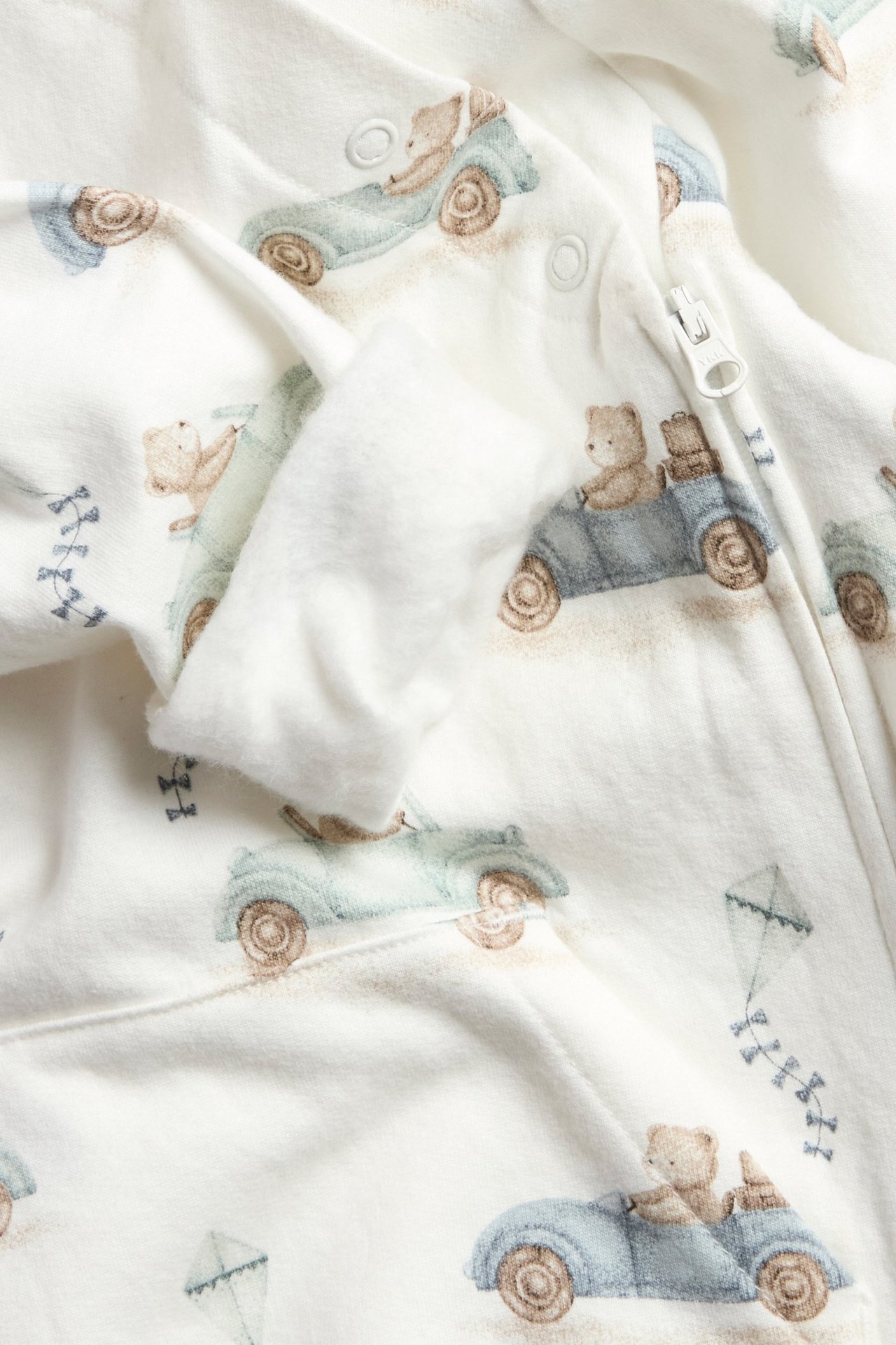 Offwhite dinosaur pattern jumpsuit for kid with zipper, hood, and ribbed cuffs.