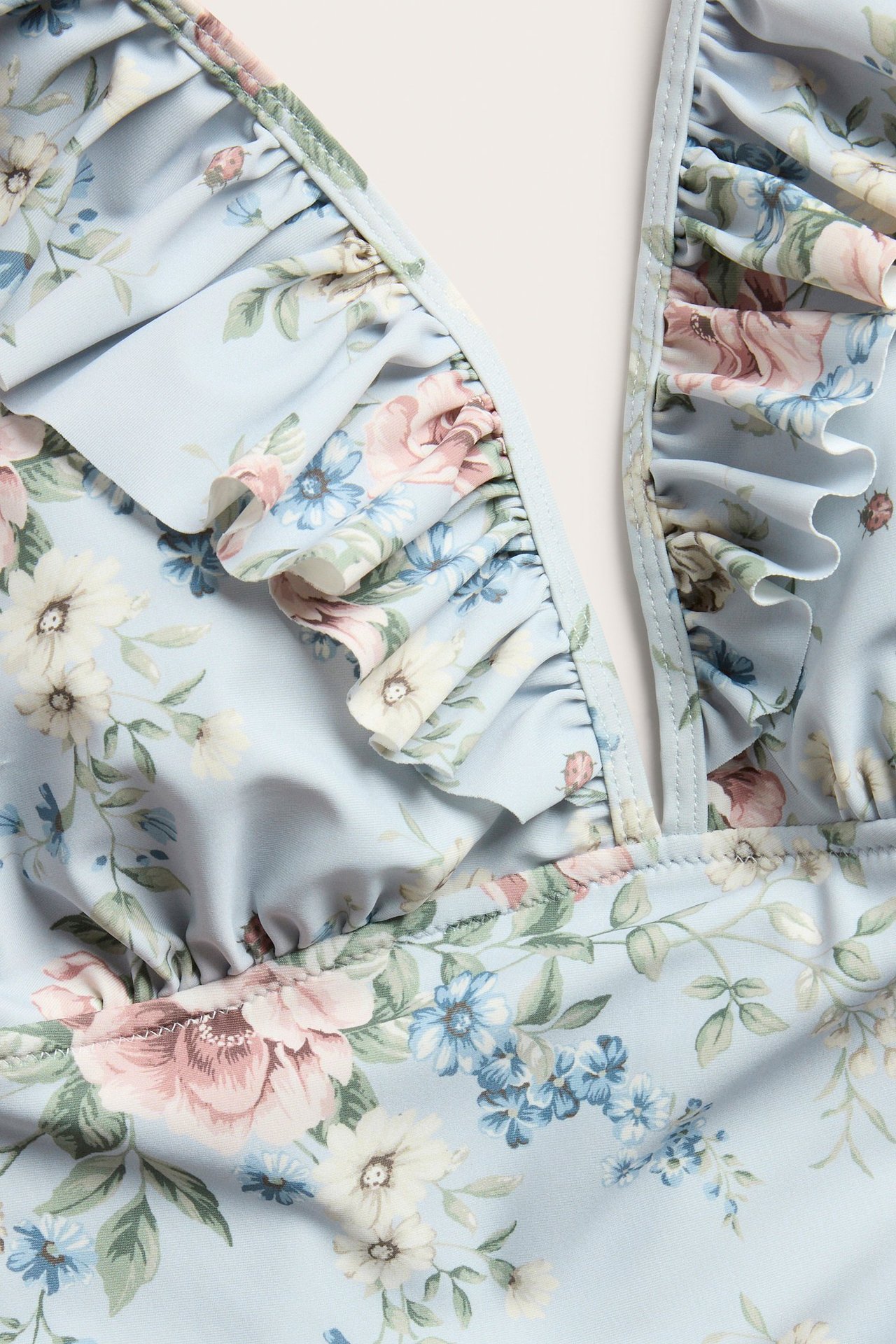 Nahaufnahme eines hellblauen geblümten Badeanzugs mit Rüschen entlang des V-Ausschnitts.