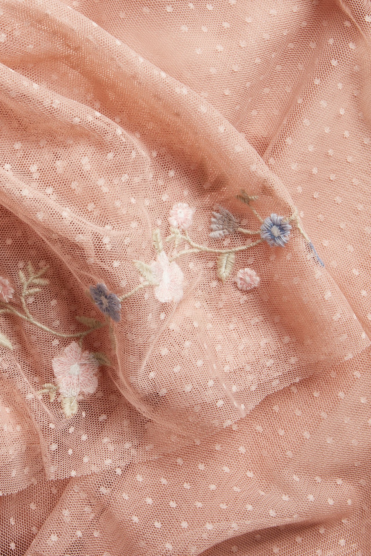 Close-up of pink dotted mesh fabric with delicate pastel floral embroidery.