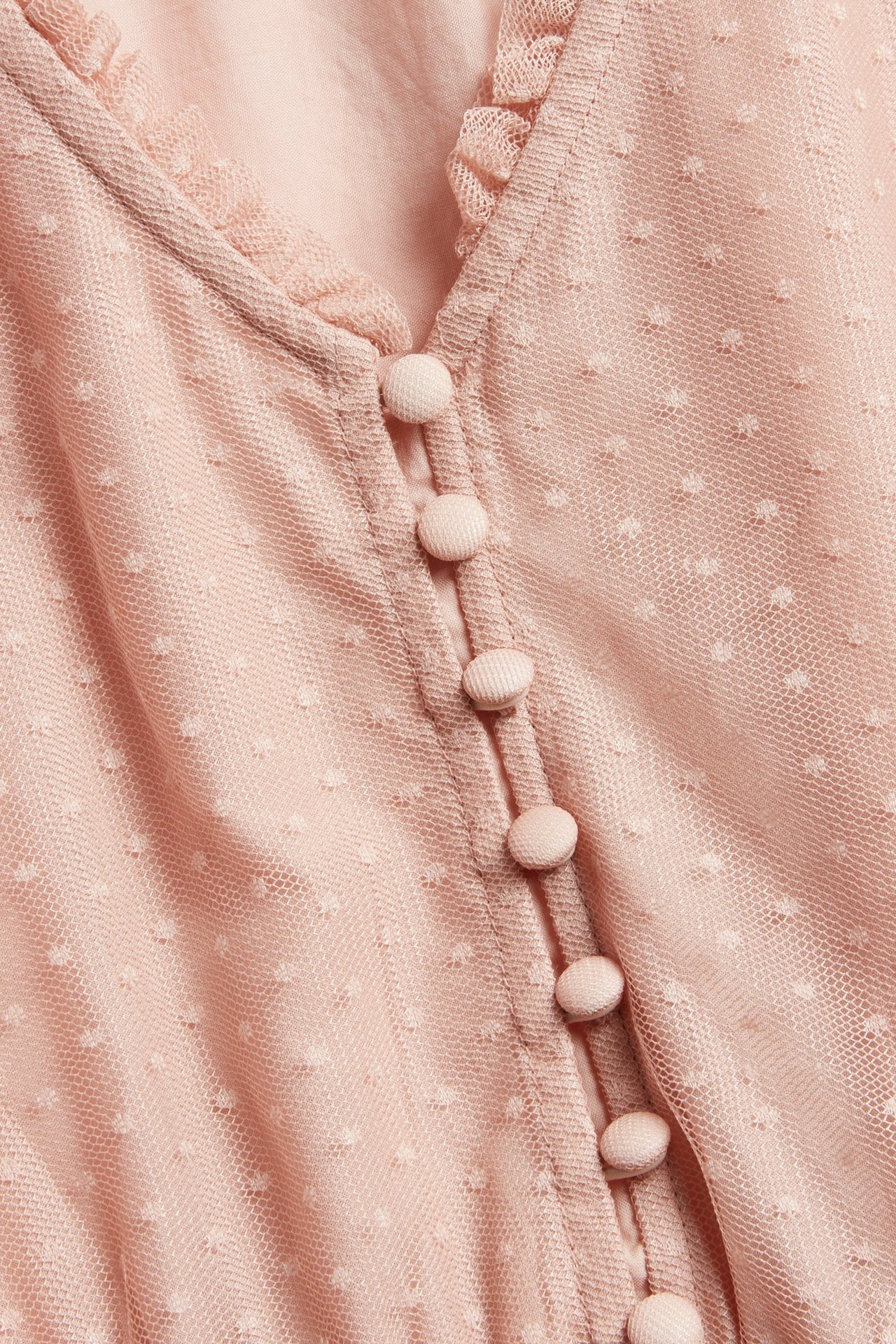 Close-up of a pink dotted mesh woman's dress with a V-neckline, small ruffle, and fabric-covered buttons.
