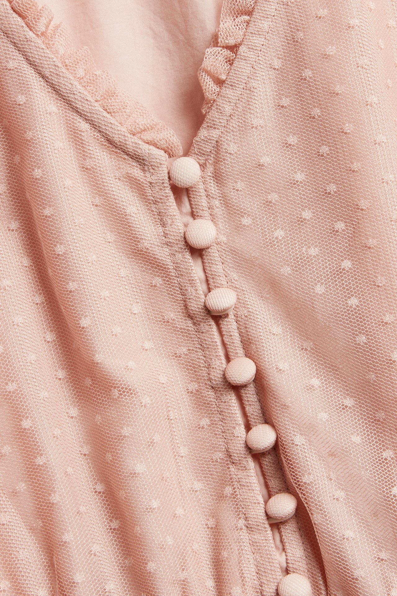 Nahaufnahme eines rosa gepunkteten Mesh-Kleides für Damen mit V-Ausschnitt, kleiner Rüsche und stoffbezogenen Knöpfen.