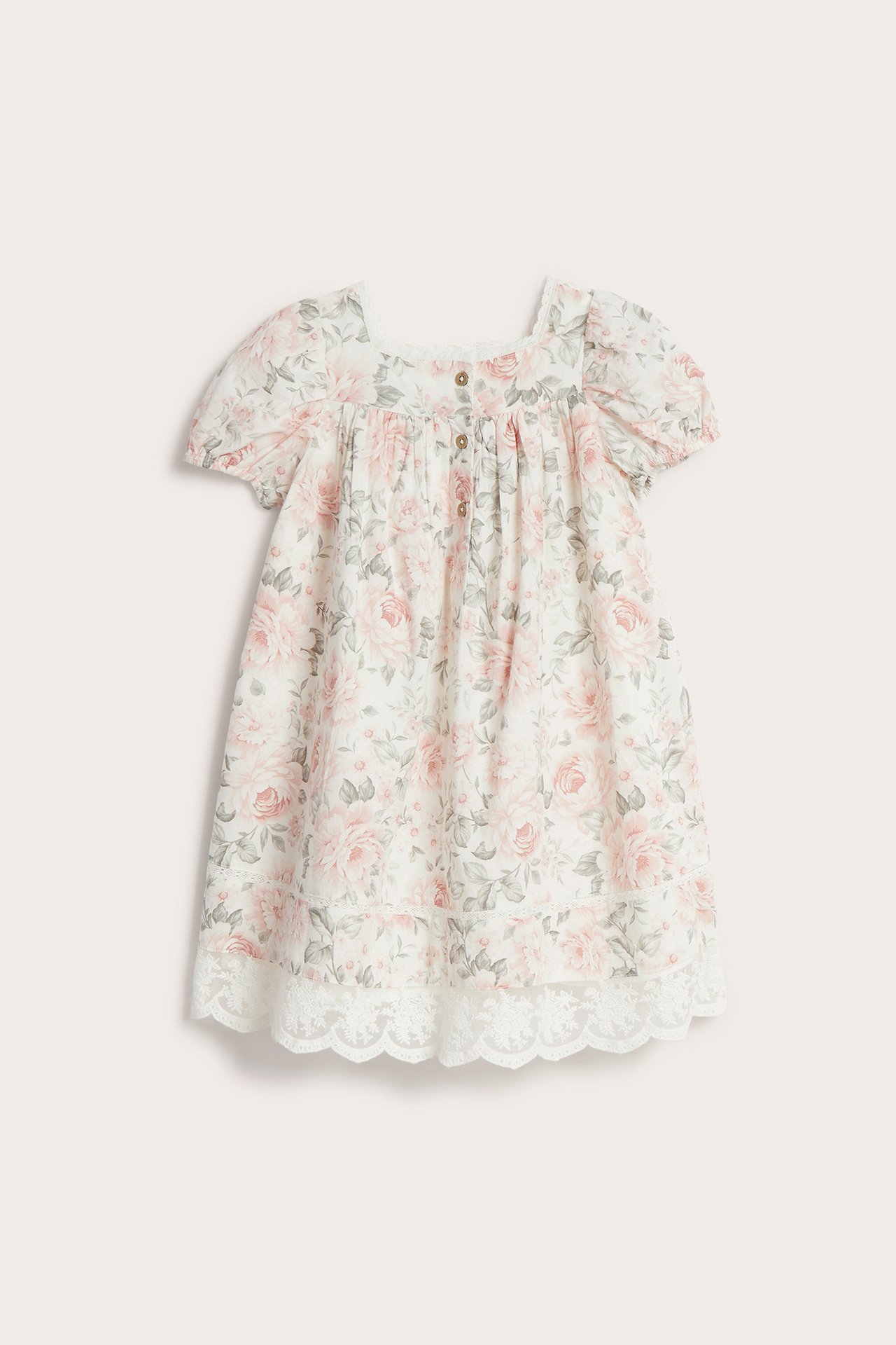 Vorderansicht eines cremefarbenen Baumwollkleides mit Blumenmuster, Spitzenausschnitt, kurzen Puffärmeln und Knöpfen vorne.