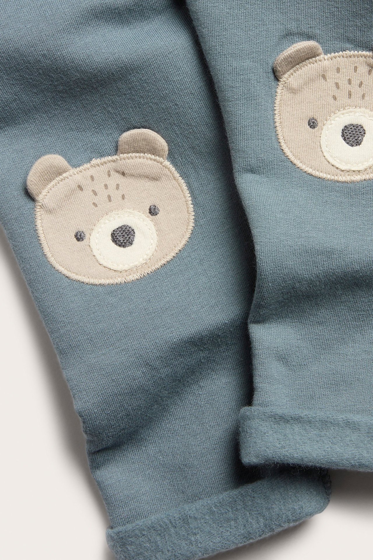 Blaue Fleece-Leggings mit Bärenapplikation, Kniepatches, vordere Dekoknöpfe und umgeschlagene Beine.
