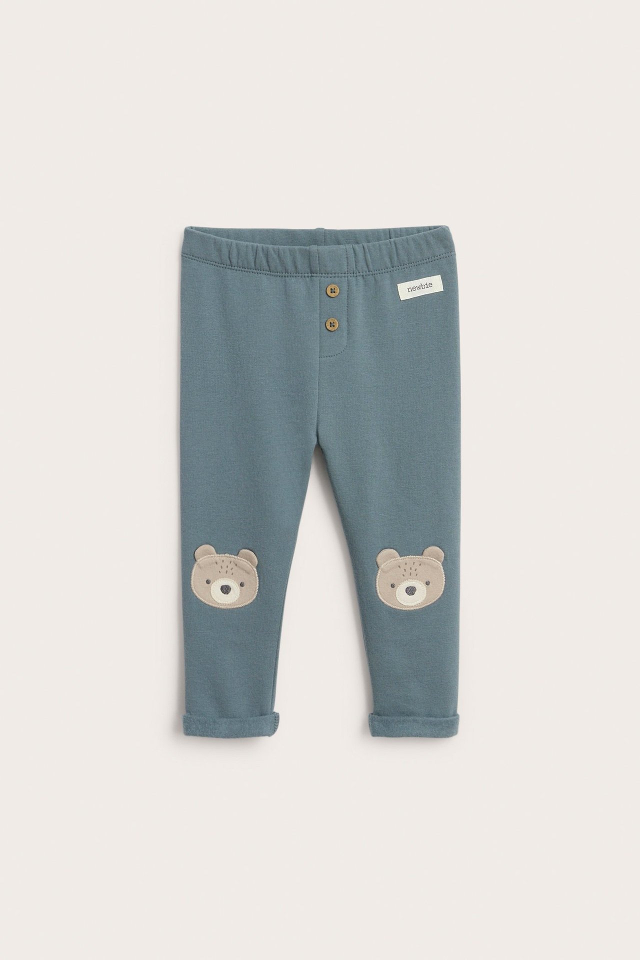 Blaue Fleece-Leggings mit Knopfleiste, elastischer Taille und aufgerollten Beinen.