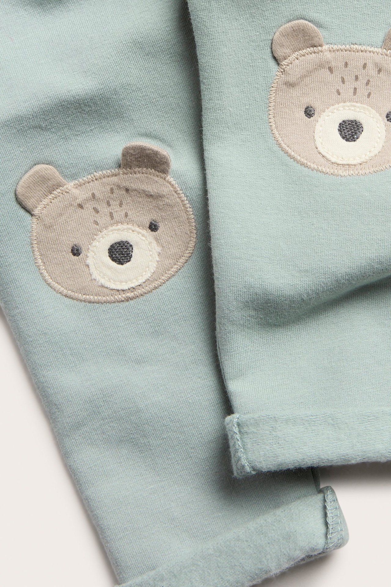 Hellgrüne Fleece-Leggings für Kinder mit Bären-Applikationen, elastischer Bund, umgekrempter Saum.