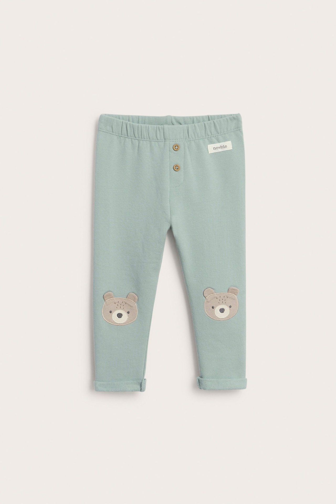 Vorderansicht von babyhellgrünen Leggings aus gebürsteter Baumwolle mit Bärenapplikationen an den Knien und Zierknöpfen.