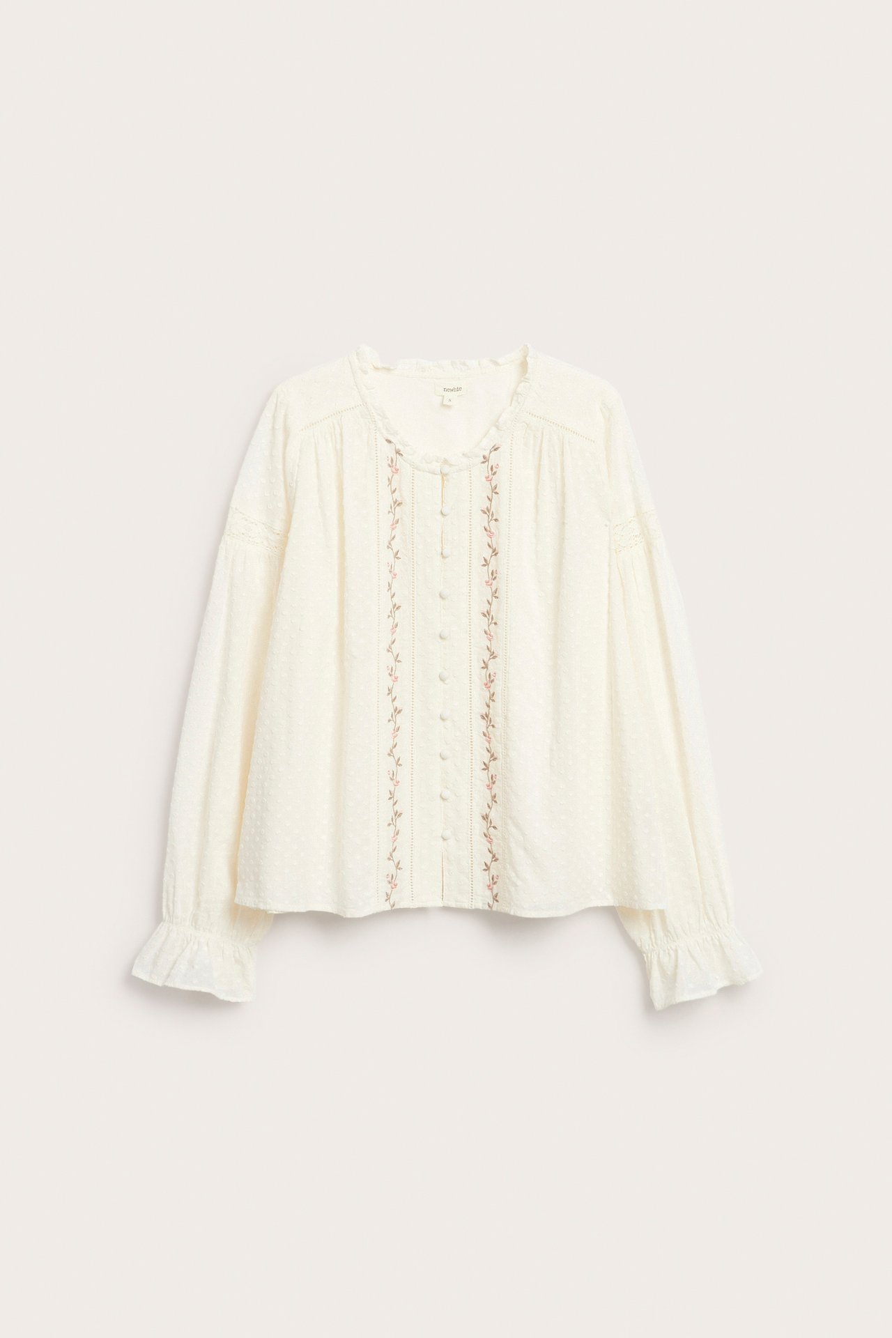 Front view of an off-white cotton blouse with floral embroidery, a ruffled collar, and ruffled elastic cuffs.