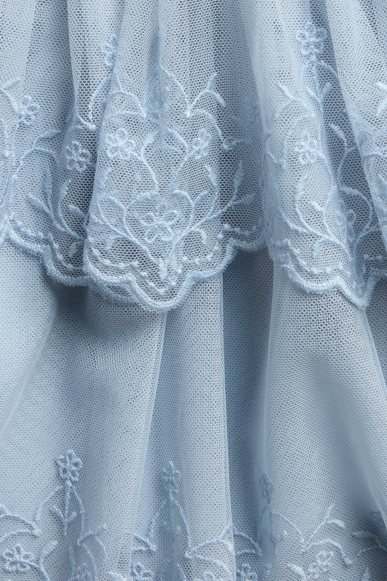 Close-up of a blue embroidered mesh skirt with tiered ruffles.