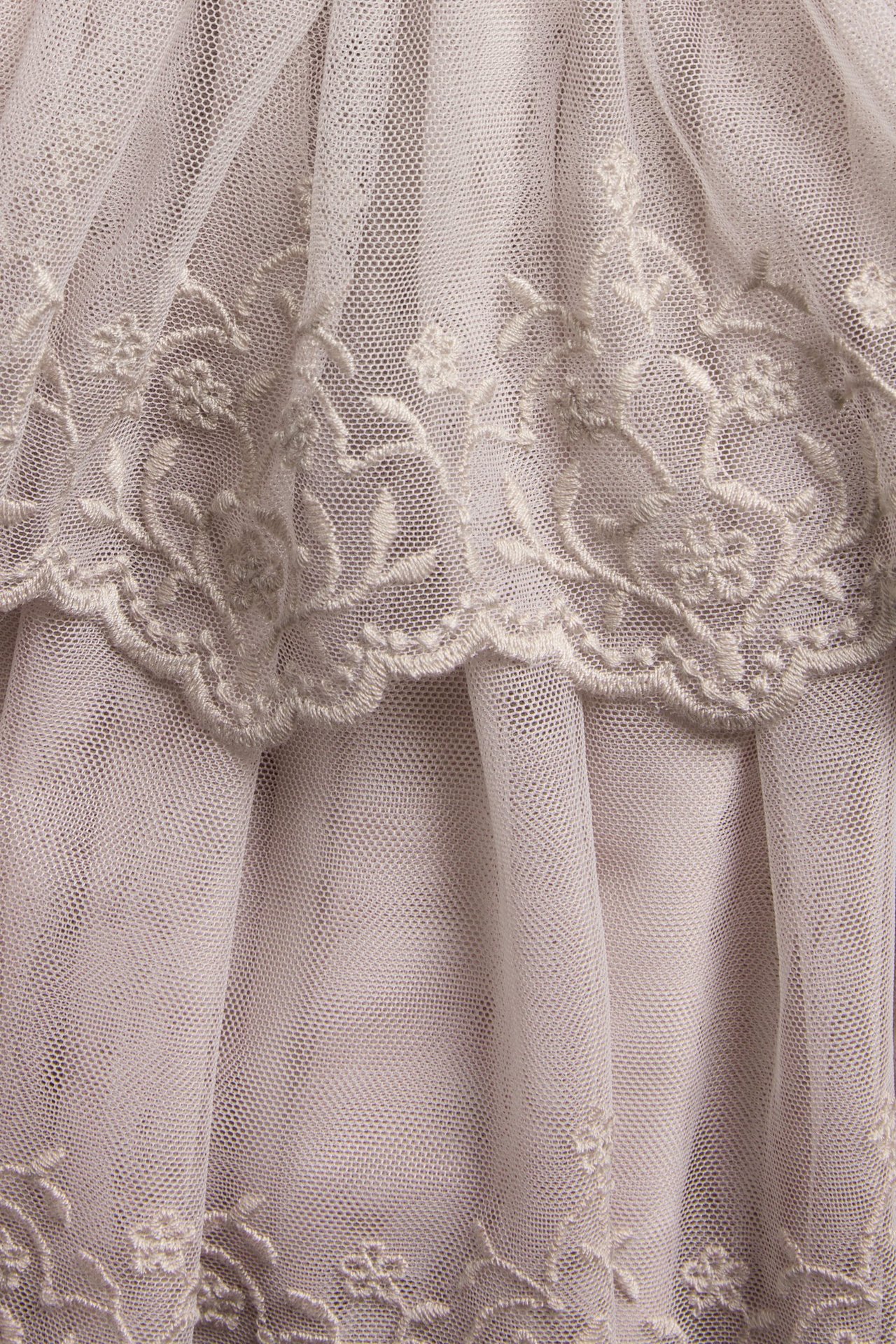 Close-up of a light lilac mesh skirt with embroidered ruffles and floral patterns.