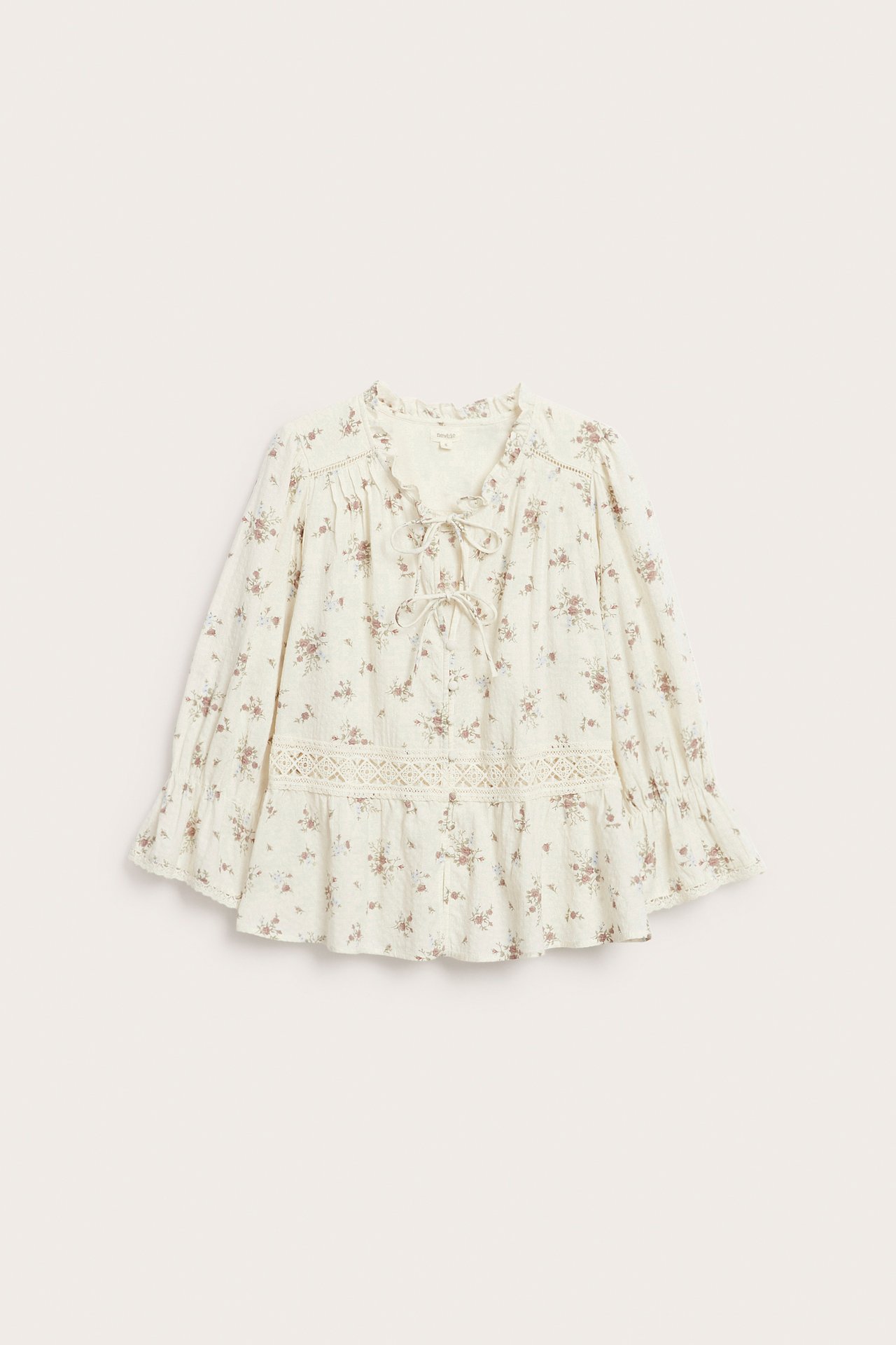 Front view of an off-white floral cotton peplum blouse with lace trim, a V-neck, and ties.
