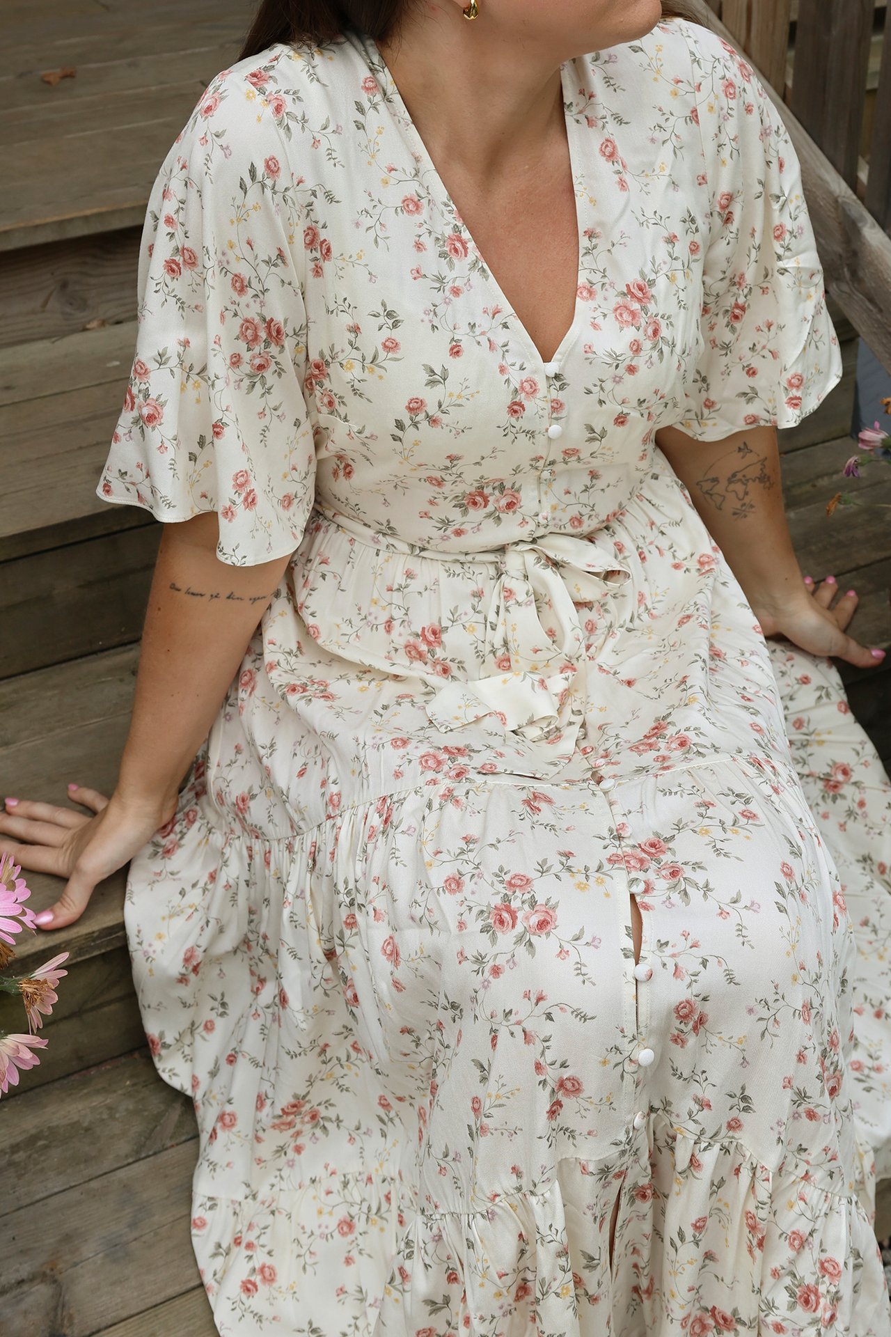 Front view: Woman in offwhite floral viscose midi dress with V-neck, short sleeves, tied belt.