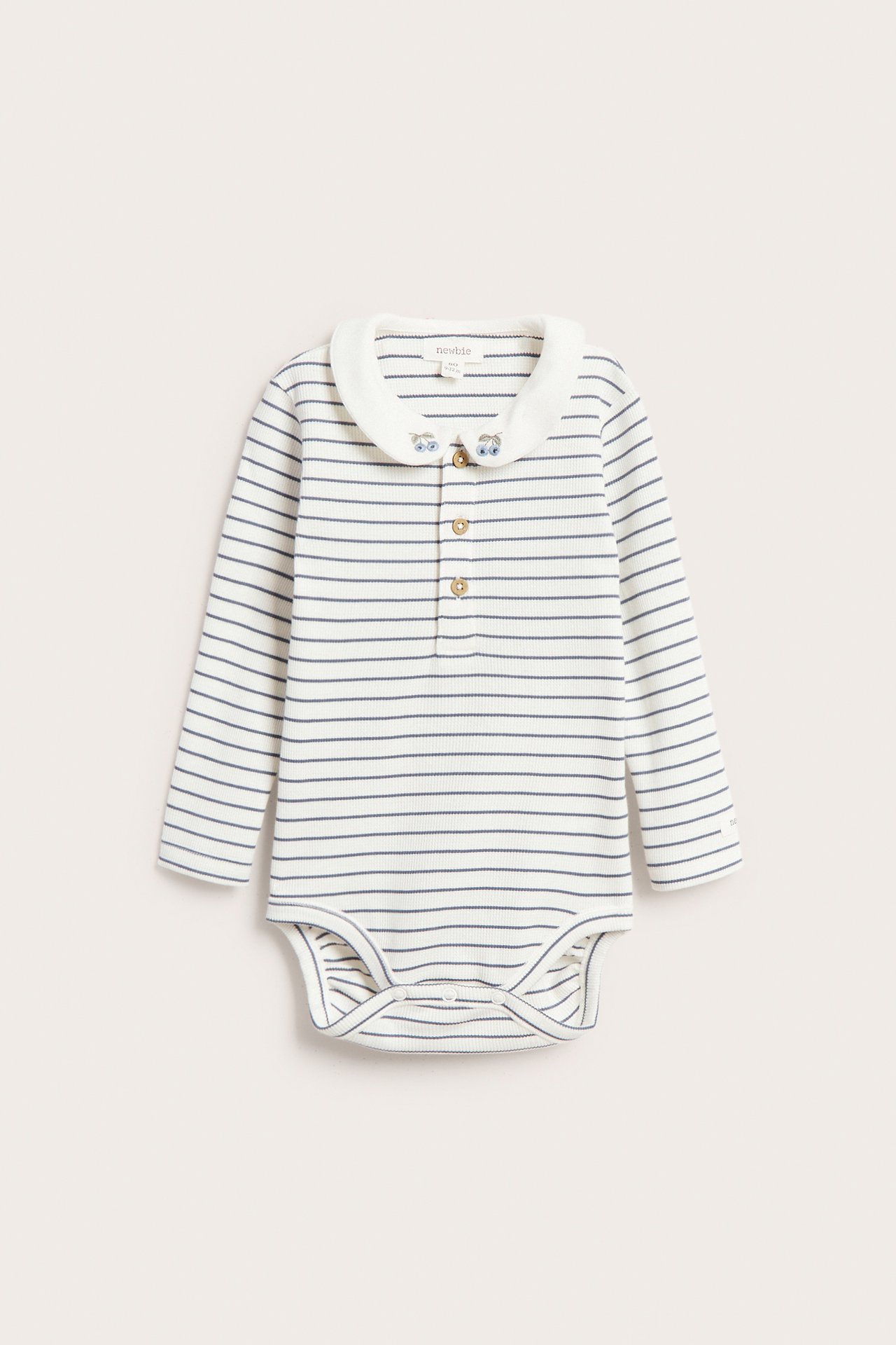 Vorderansicht eines offwhite gestreiften gerippten Babybodys mit langen Ärmeln, besticktem Kragen und Knopfleiste.