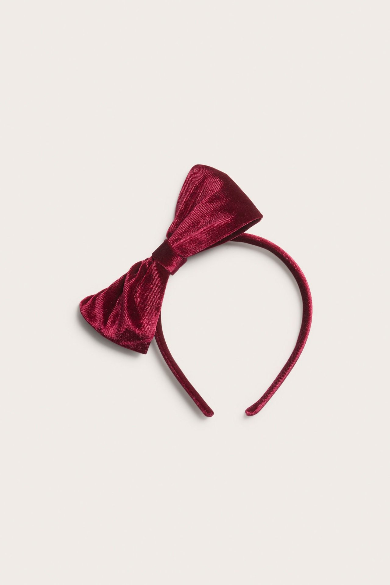 Front view of a dark red velvet headband with a large, matching velvet bow.