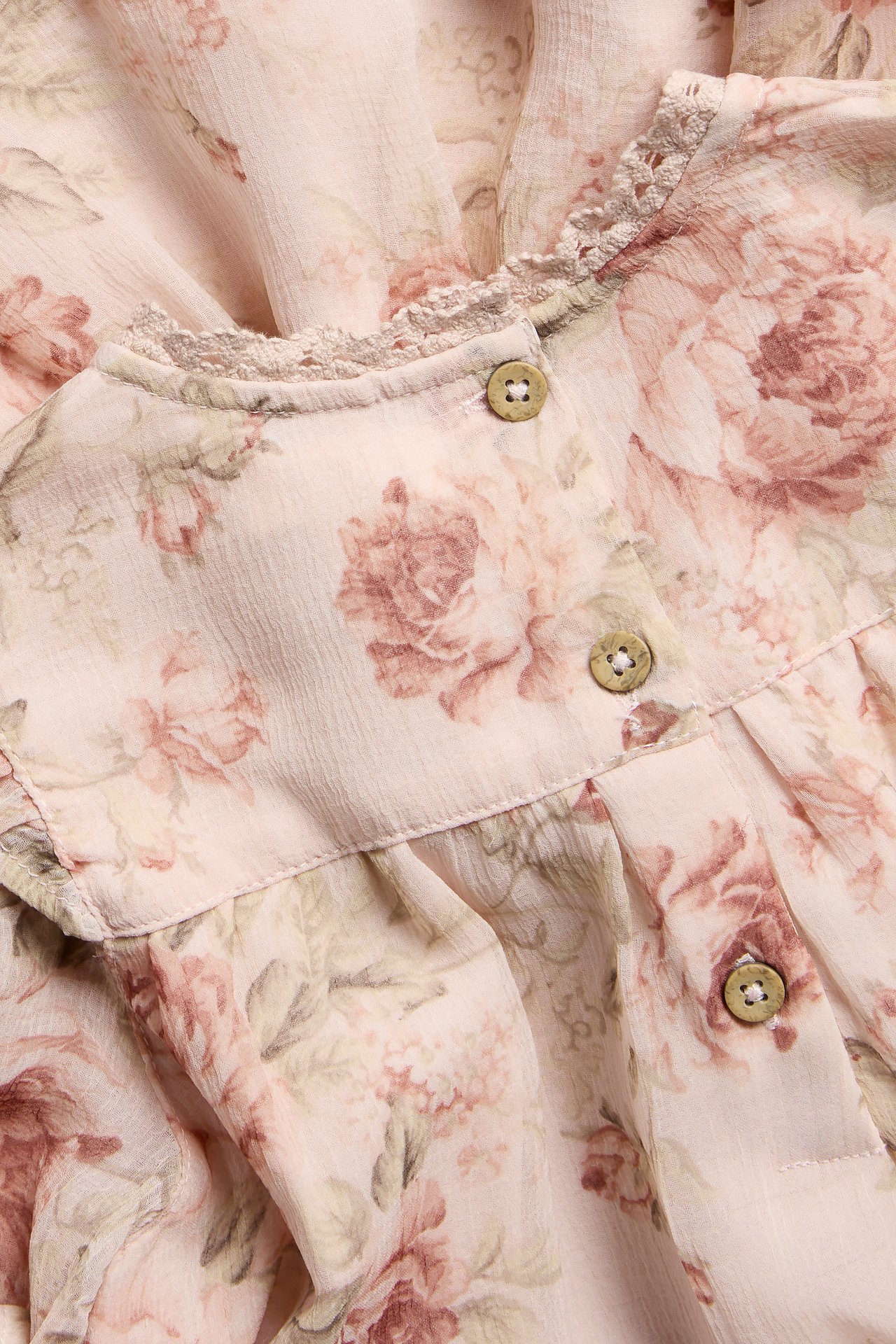Close-up front view of a pink floral chiffon dress with wooden buttons and lace trim neckline.