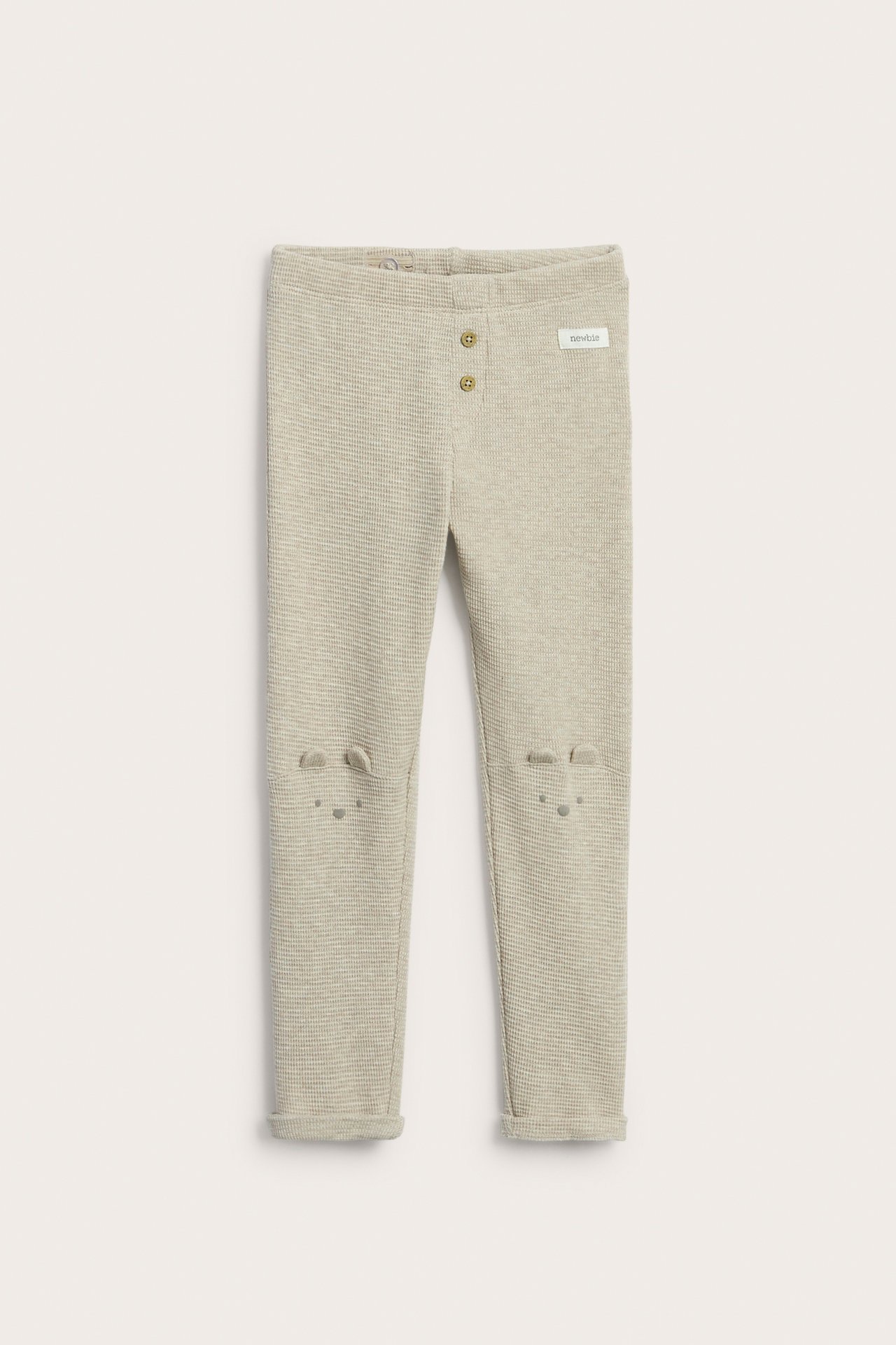 Vorderansicht von melange-beige Waffelstrick-Kinderleggings mit Zierknöpfen und Tierohren an den Knien.