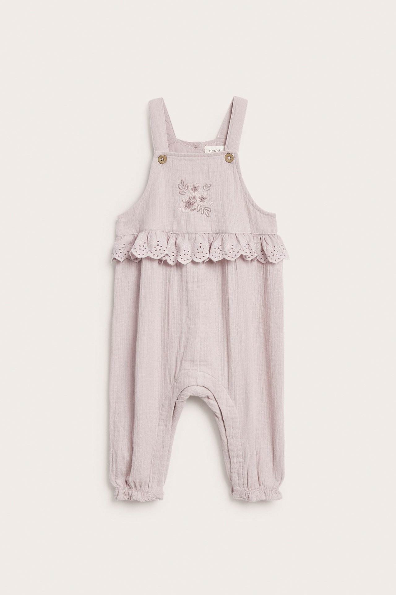 Vorderansicht eines lila Baby-Overalls mit Blumenstickerei und Rüsche mit Lochmuster.