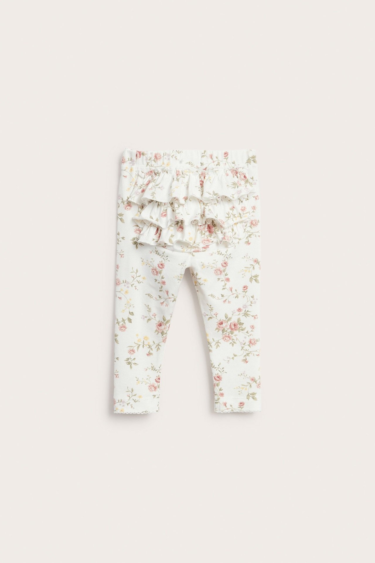 Vorderansicht: Baby-Leggings in Cremeweiß mit Blumenmuster, drei Rüschen hinten und Gummibund.
