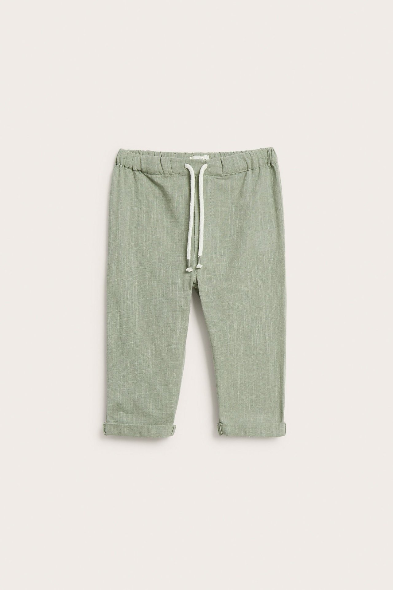 Front view of kid's dark green textured woven cotton pants with elastic waist, white drawstring, and rolled-up cuffs.