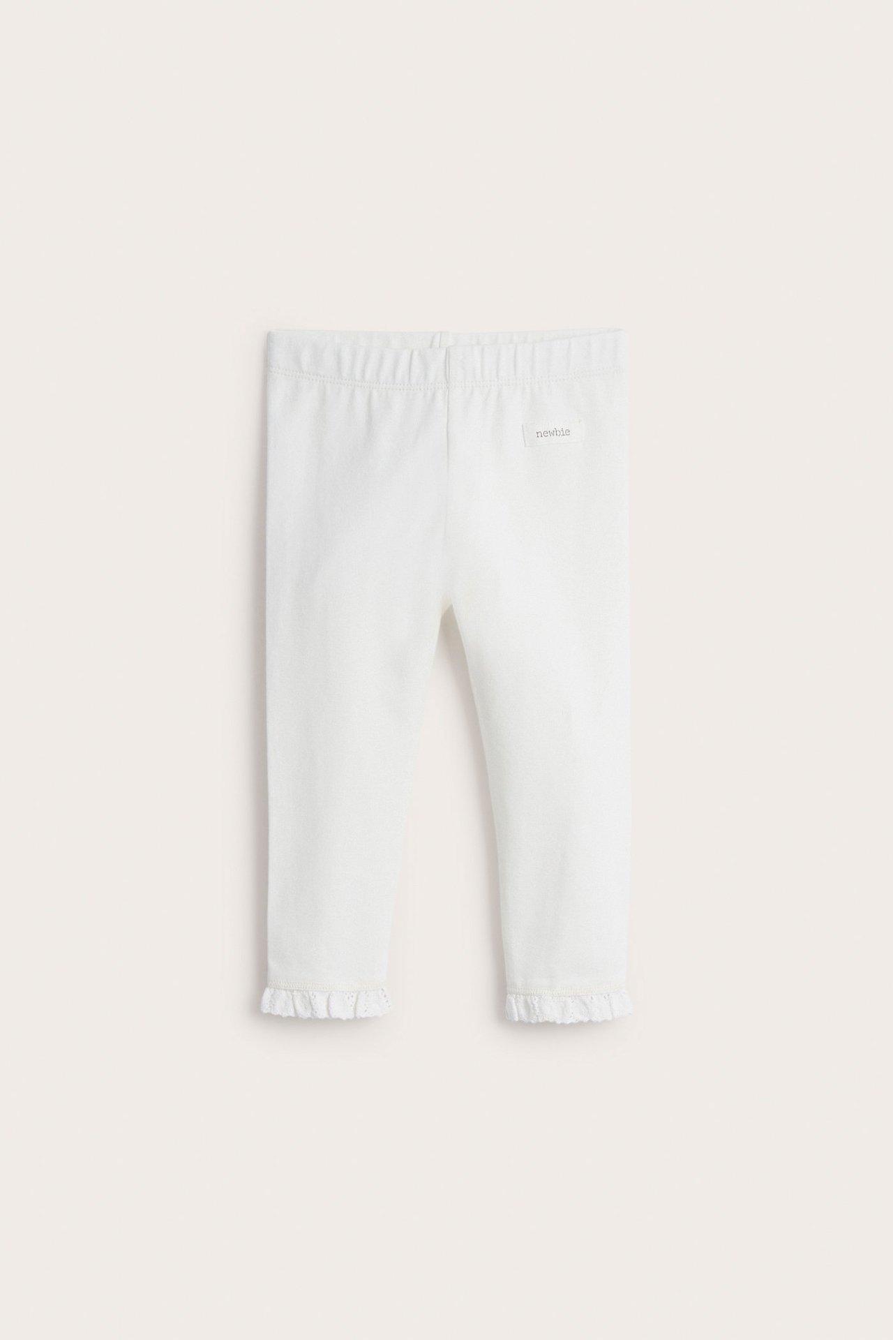 Front view of off-white baby leggings in soft jersey with elastic waist and lace trim at cuffs.