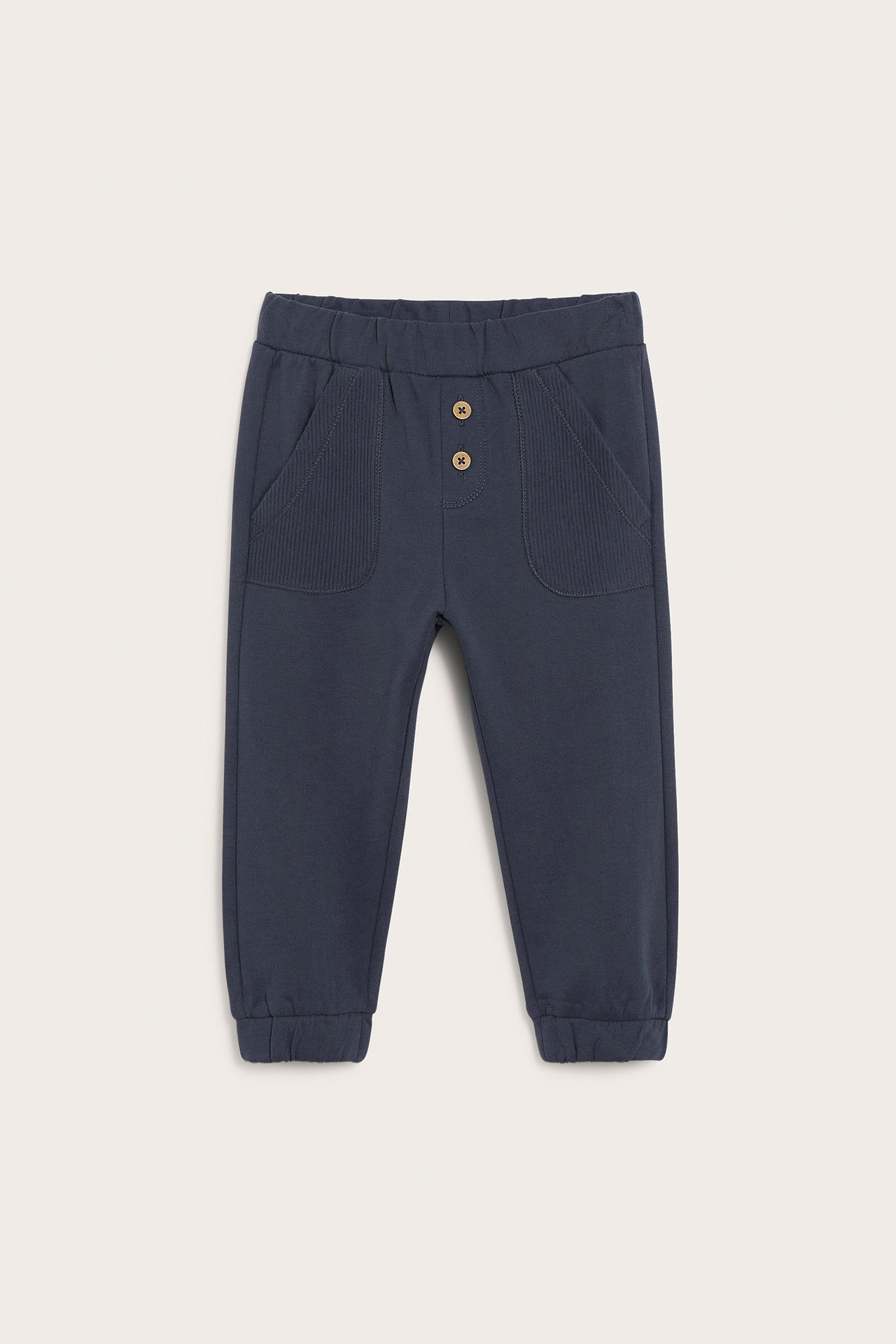 Vorderansicht von dunkelblauen Kinder-Sweatpants mit Zierknöpfen und gerippten Taschen.
