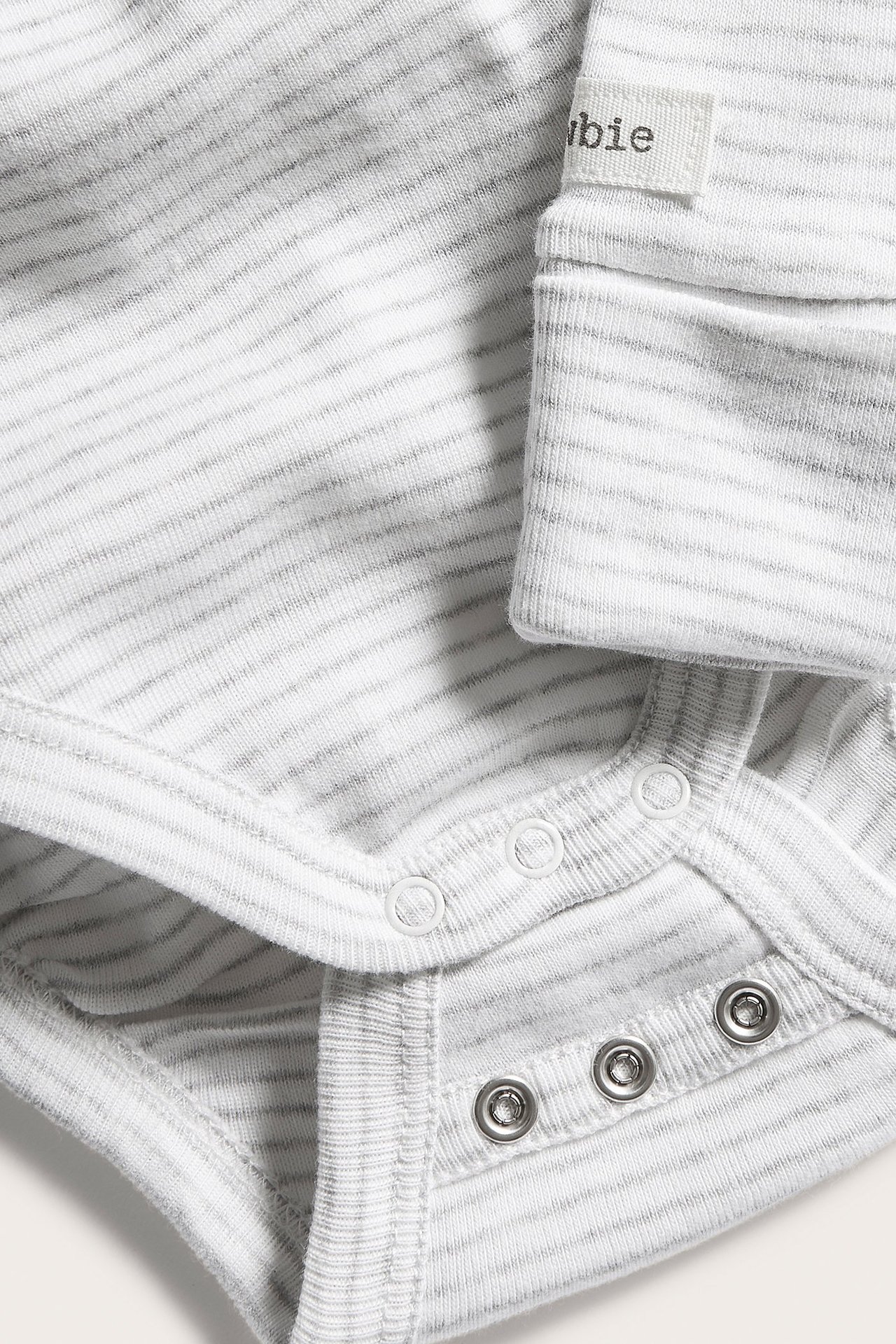 Nahaufnahme eines babygrau melierten gestreiften Baumwoll-Wickelbodys mit Druckknöpfen.