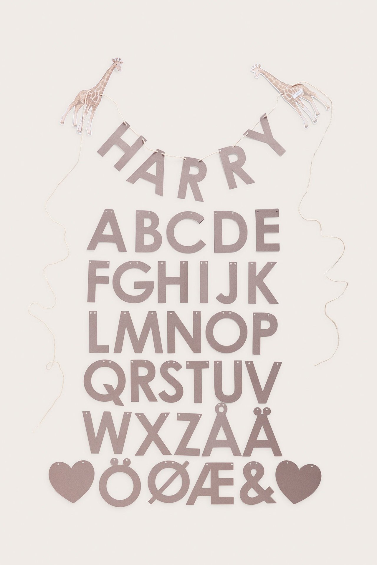 Draufsicht: braunes Papiergirlanden-Set mit Buchstaben, zwei gemusterten Giraffen und Schnur.