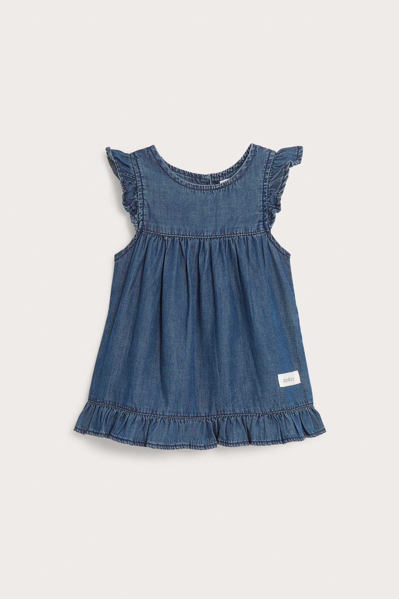 Front view of a baby's blue denim dress with ruffles on the shoulders and a ruffled cotton hem.
