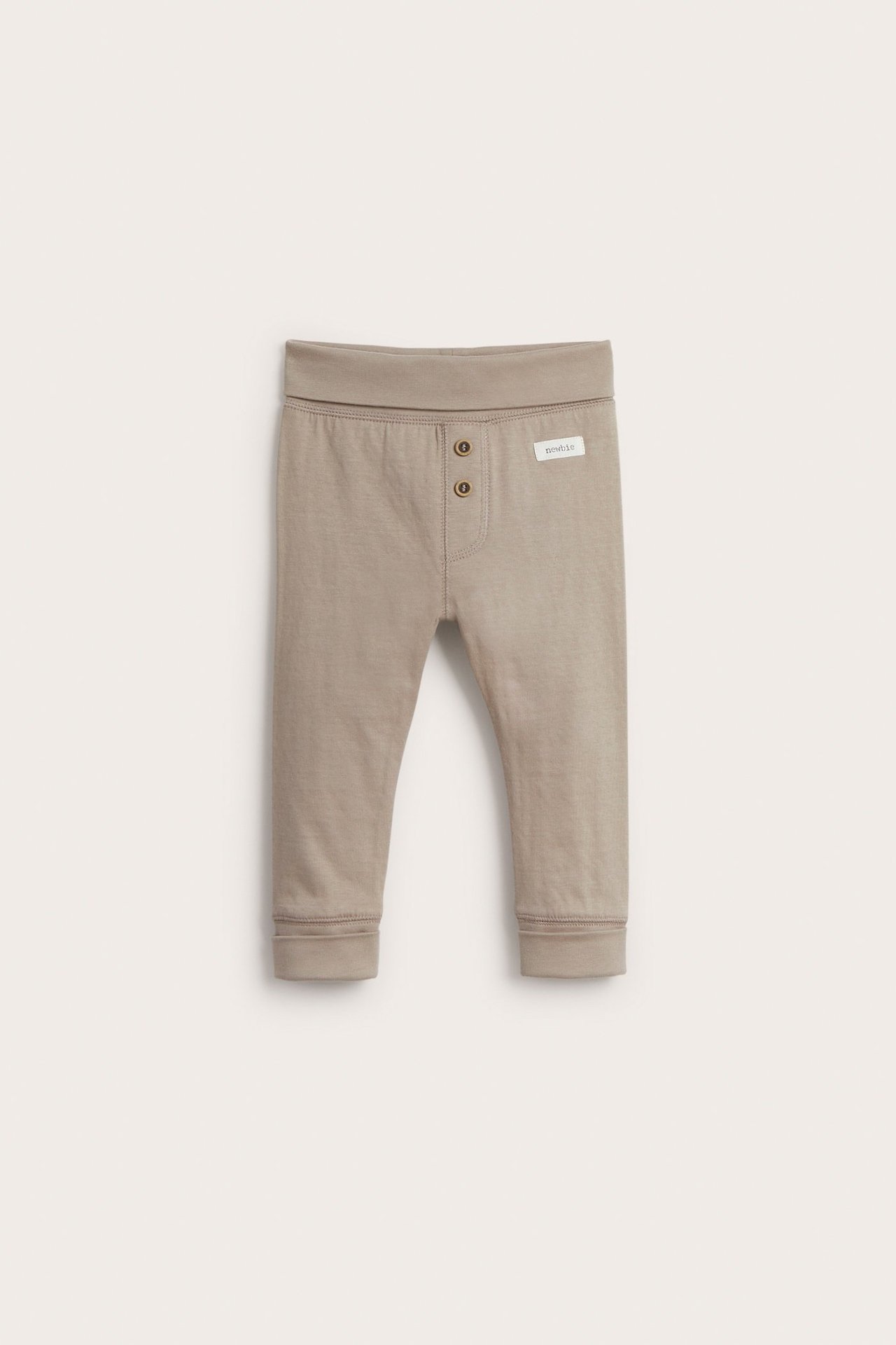 Front view of beige baby cotton leggings with fold-down waist, two decorative buttons, and ankle cuffs.