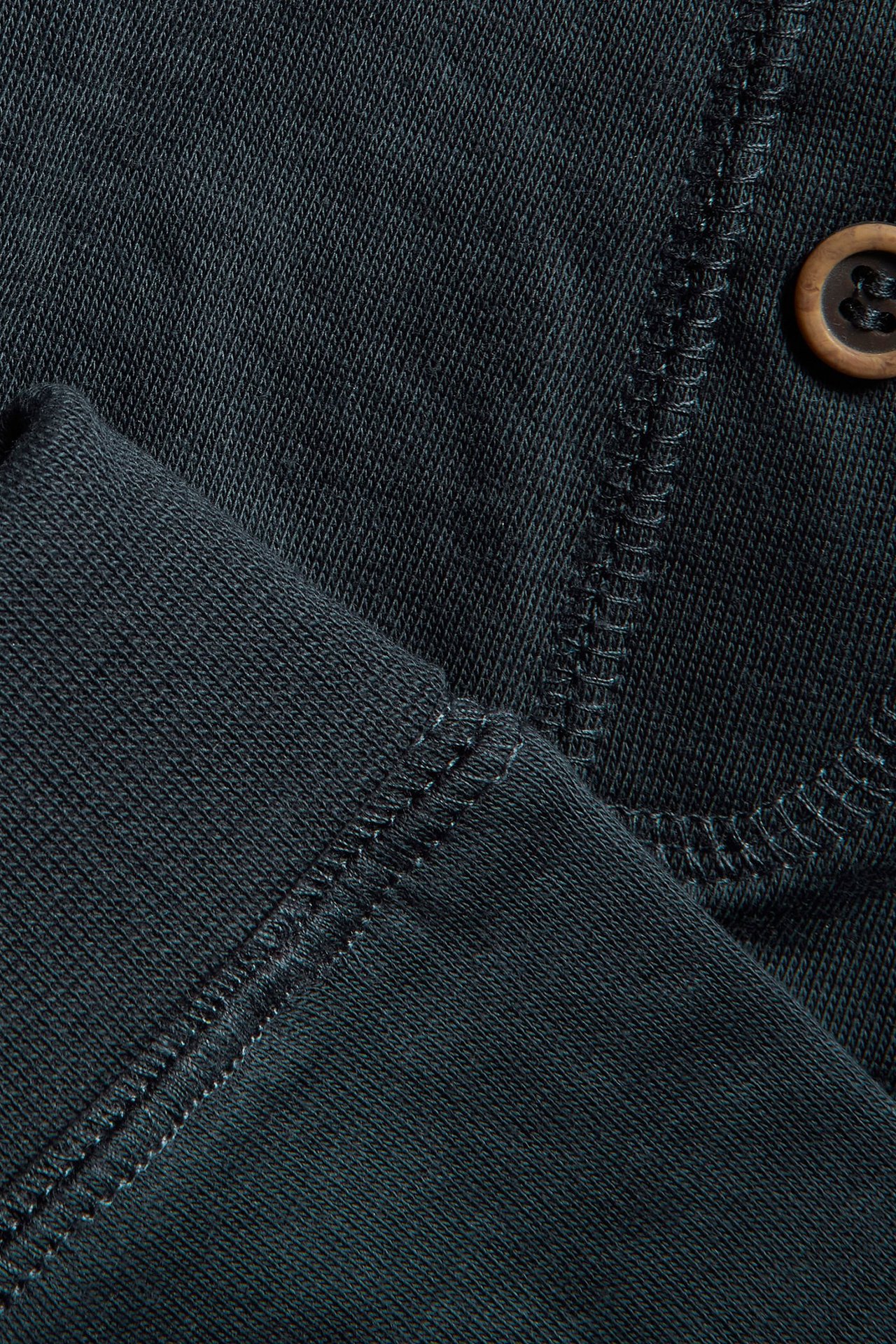 Close-up of dark blue cotton baby leggings with visible stitching and a decorative brown button.