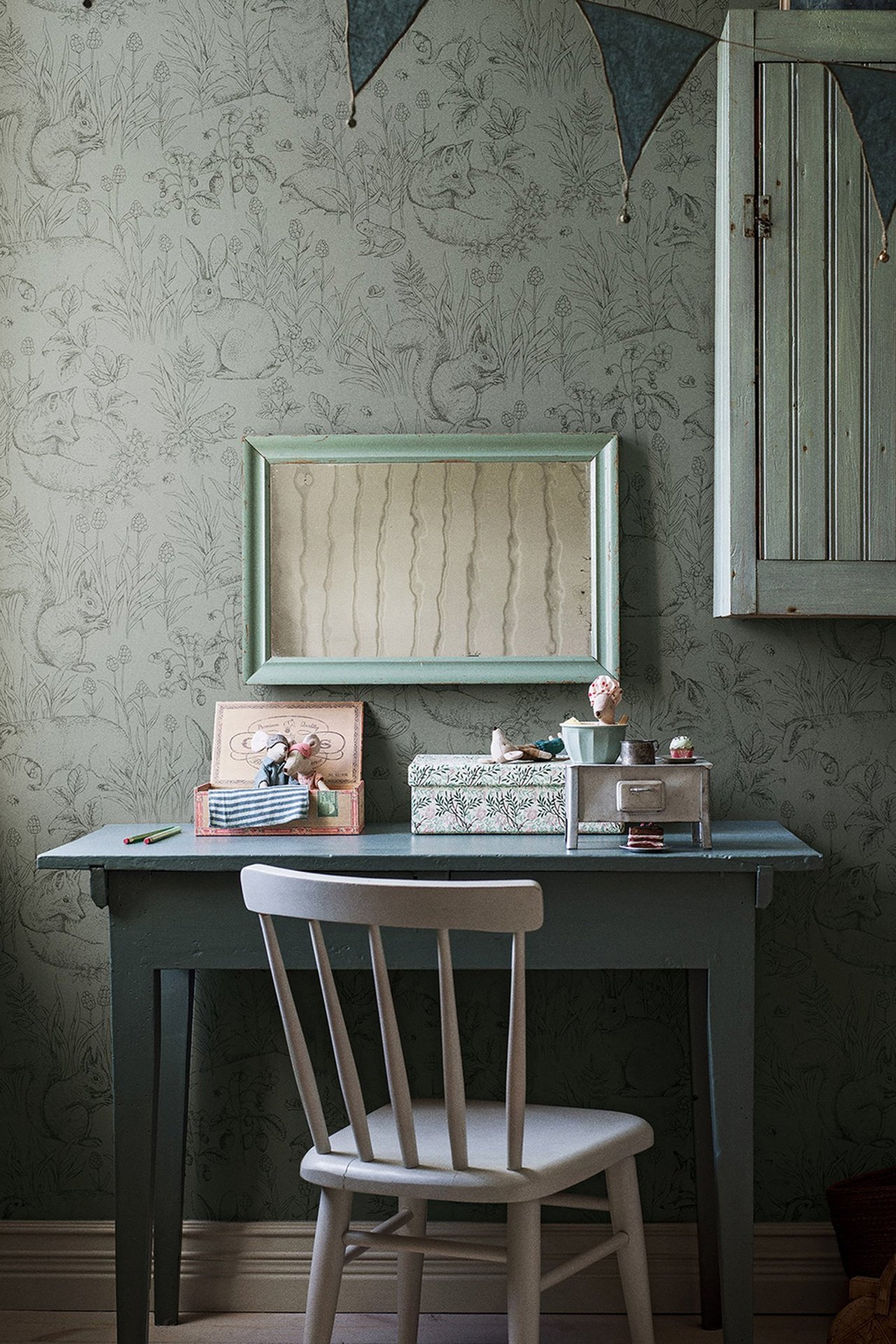 Vorderansicht einer grünen Vliestapete mit detailliertem Waldtiermuster an einer Wand.