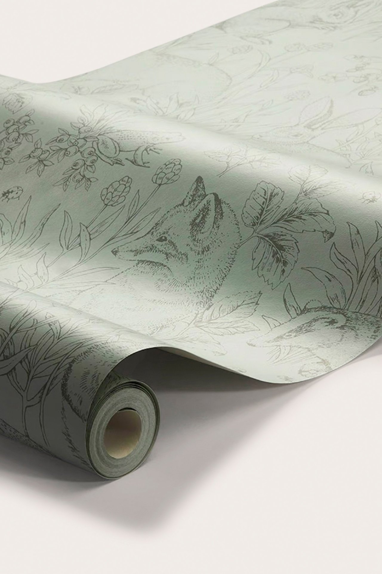 Close-up of a roll of green animal-patterned non-woven wallpaper, showing foxes and forest motifs.