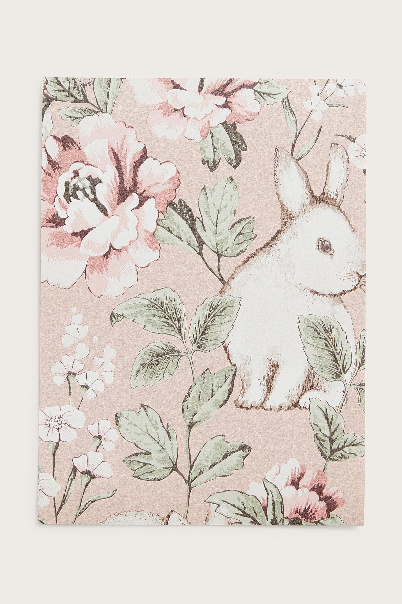 Close-up of a pink non-woven wallpaper sample with a white rabbit, pink flowers, and green leaves pattern.