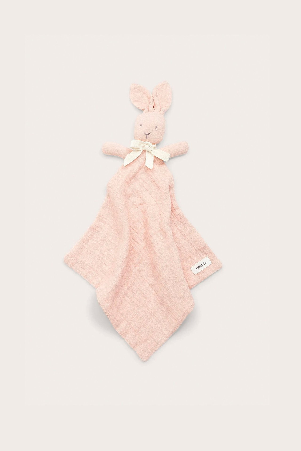 Draufsicht auf ein hellrosa Baumwoll-Schmusetuch für Babys mit Hasenkopf und weißer Schleife.