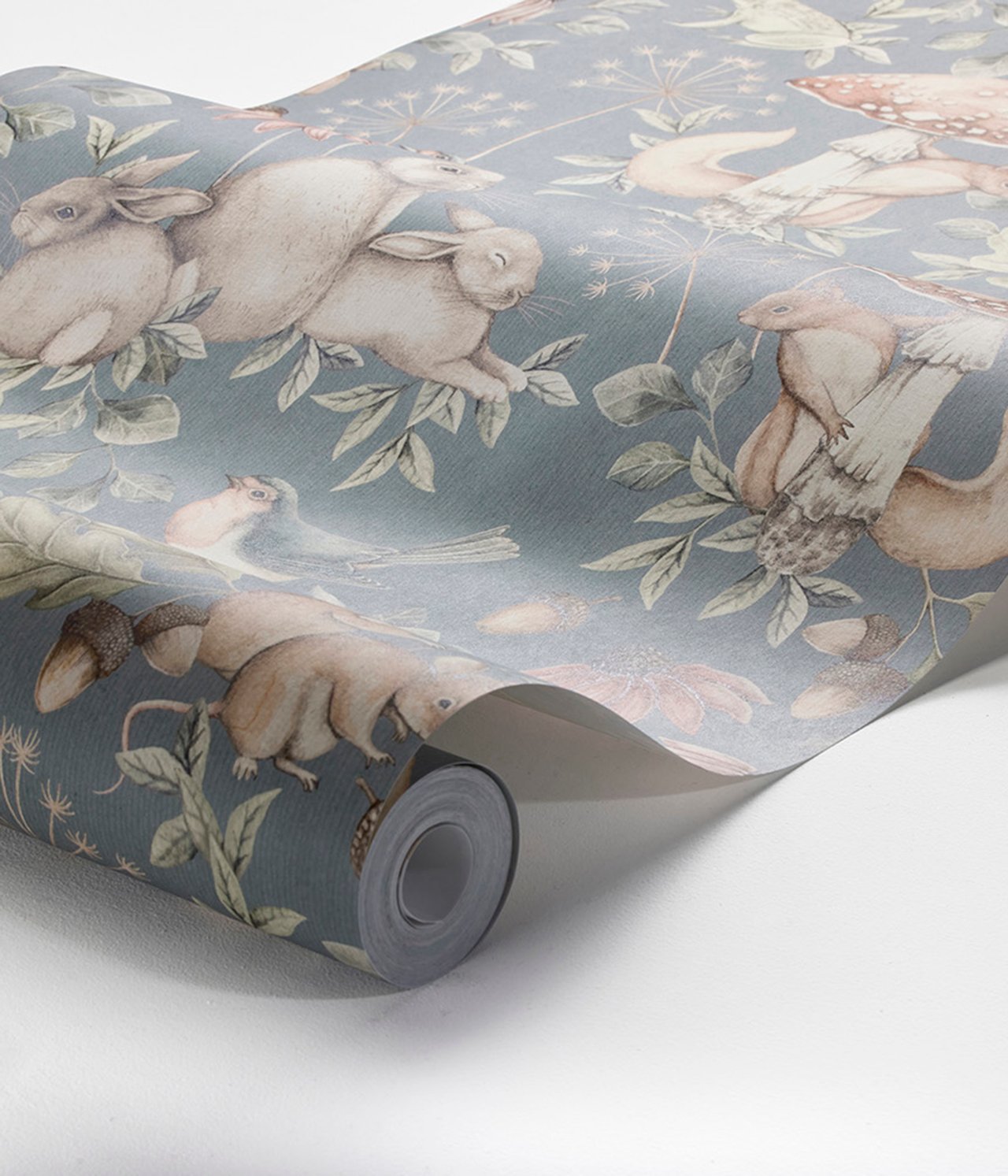 Nahaufnahme einer blauen Vliestapetenrolle mit Waldtier- und Pflanzenmuster.