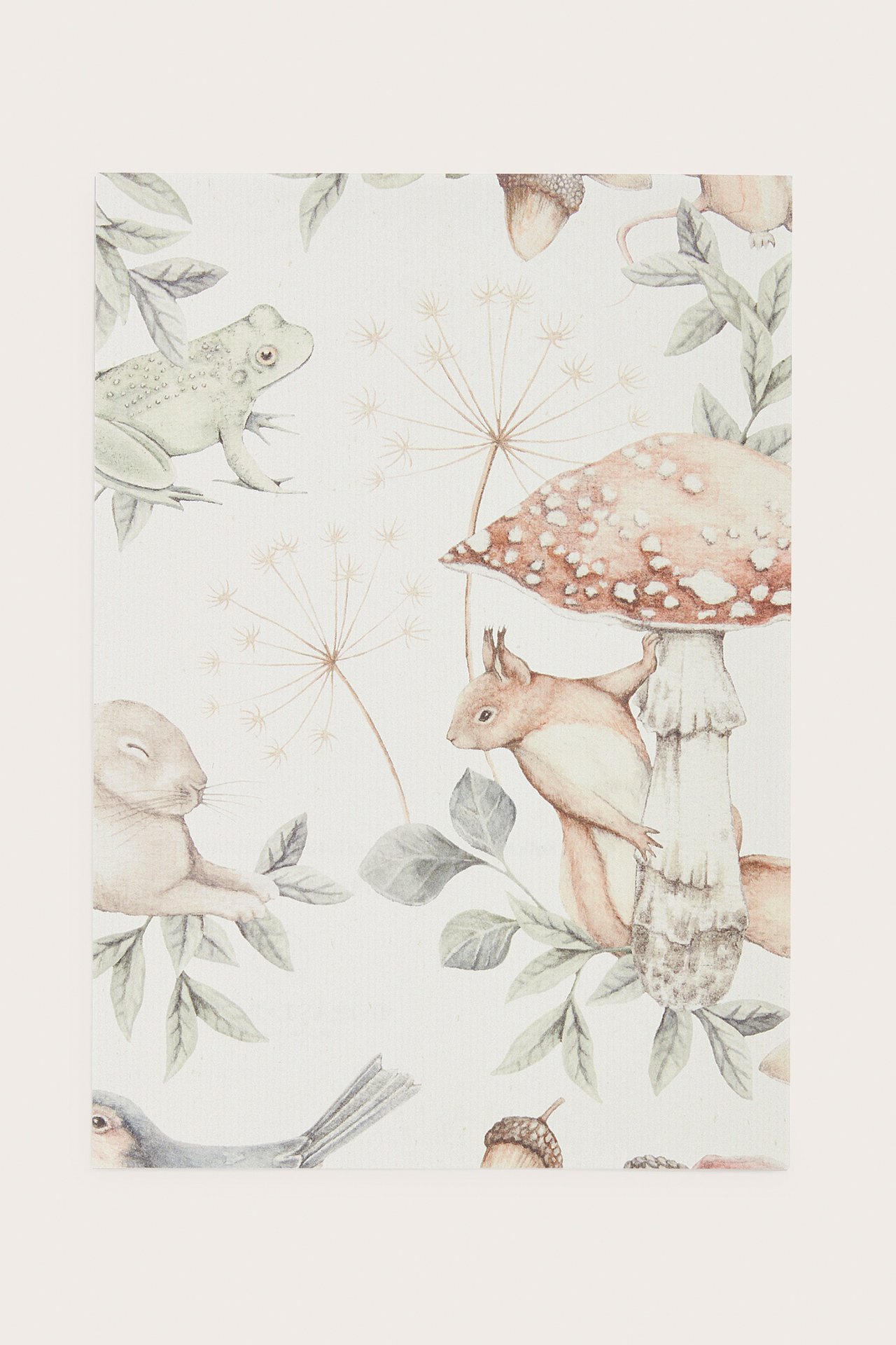 Close-up of an offwhite non-woven wallpaper sample with a pattern of forest animals and plants.