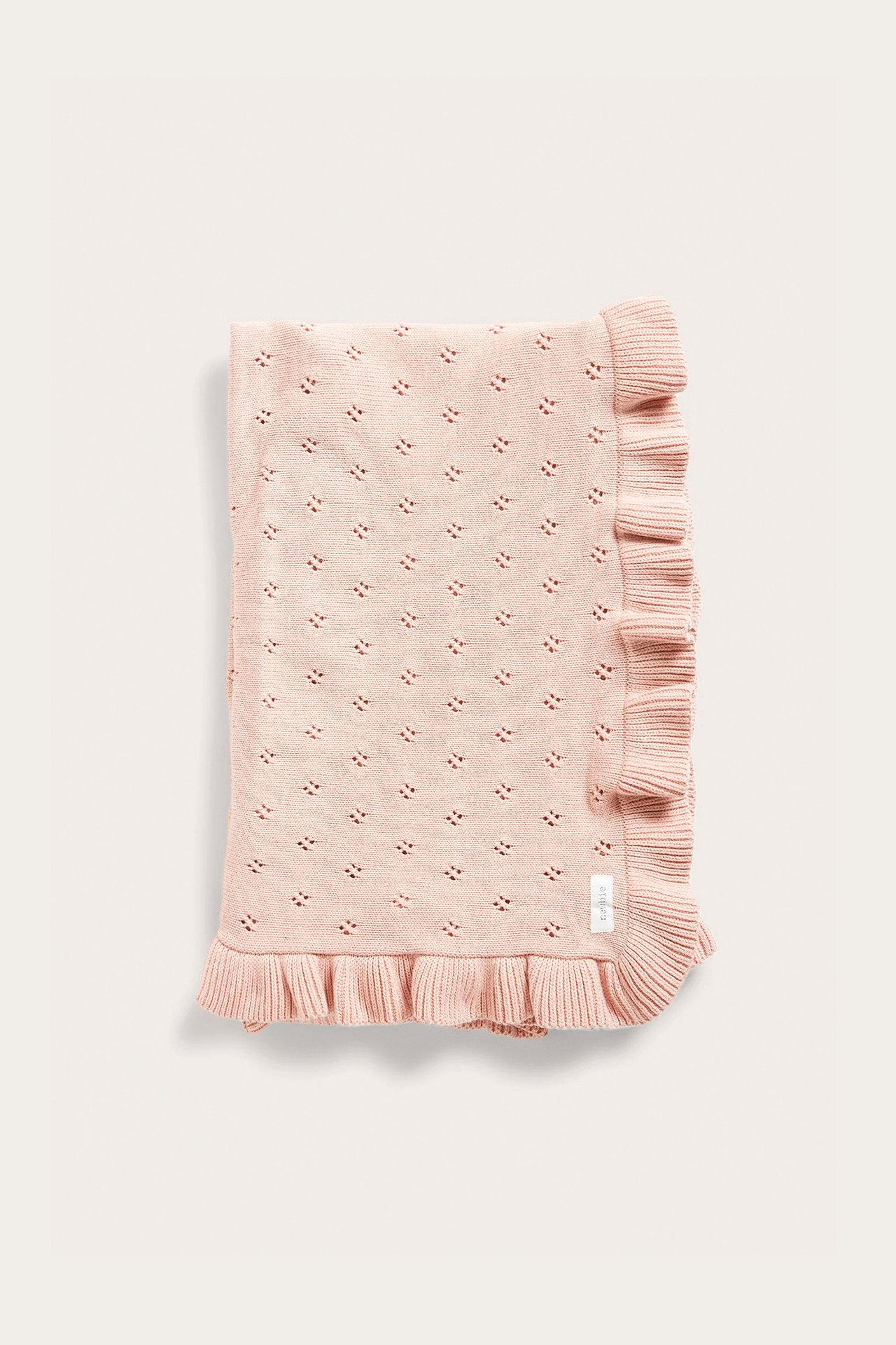 Front view of a folded light pink organic cotton baby blanket with knitted hole pattern and ruffle edge.