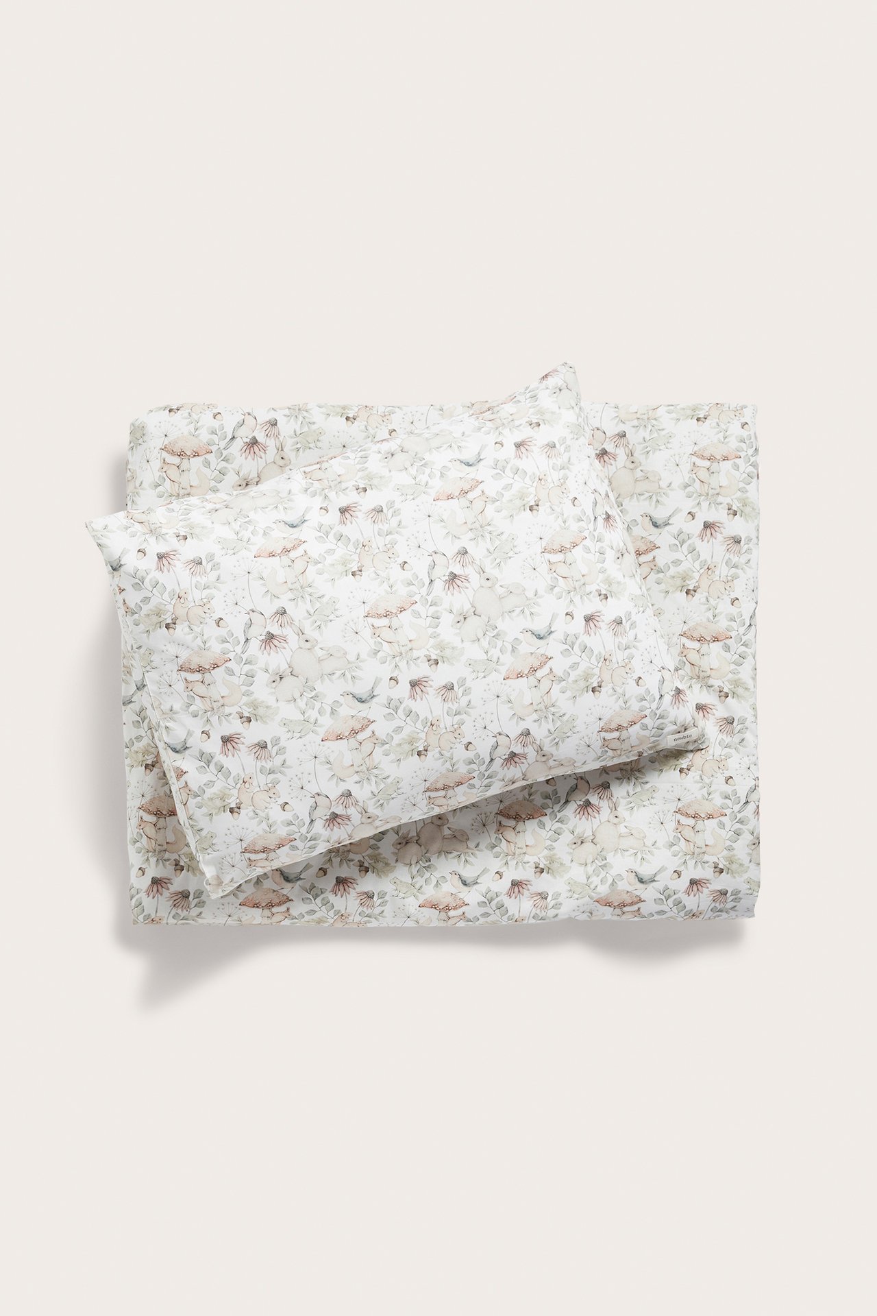Top-down view of a light beige cotton duvet cover set with a forest and animal print.