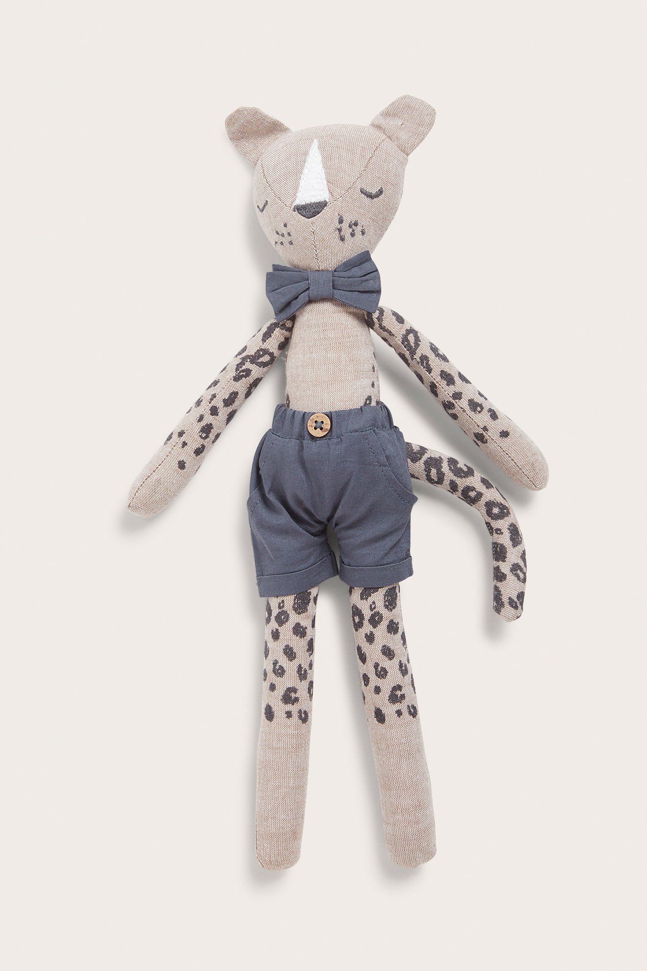 Front view of a beige leopard stuffed animal with dark grey spots, wearing grey shorts and a bow tie.
