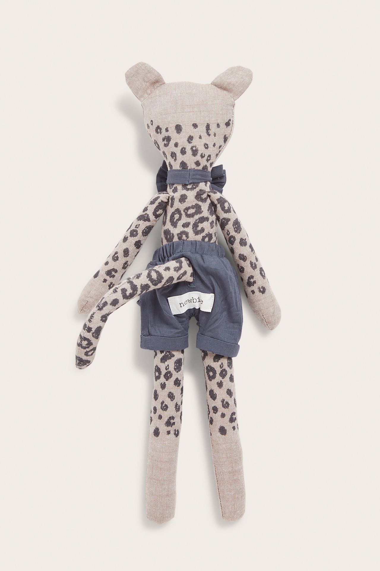 Front view of a beige leopard print stuffed animal wearing blue shorts and a blue bow tie.