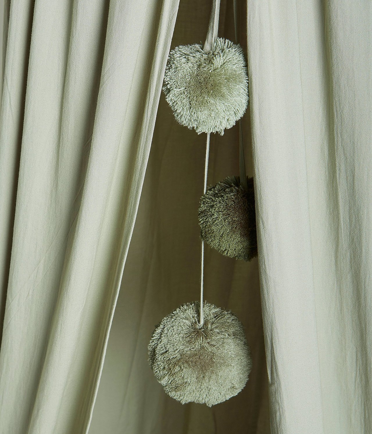 Nahaufnahme eines dunkelgrünen Leselagers mit drei hängenden Pompons.