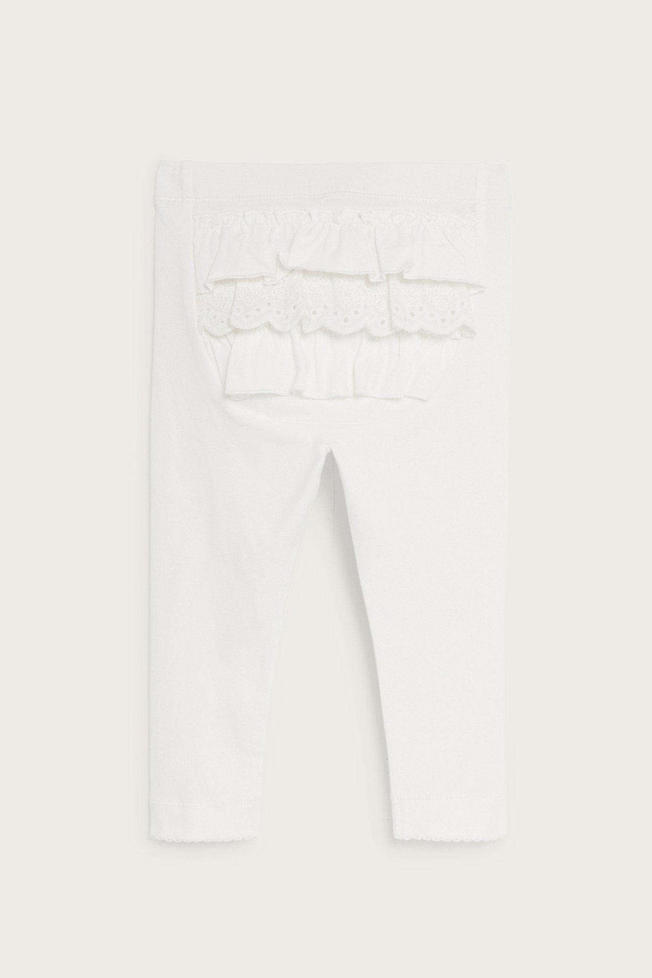 Back view of offwhite baby leggings with elastic waist, ruffles, and lace trim on the back.
