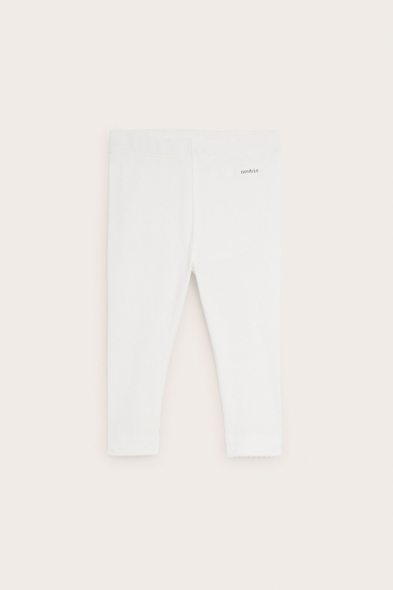Front view of off-white baby leggings with elastic waist and picot trim at leg openings.