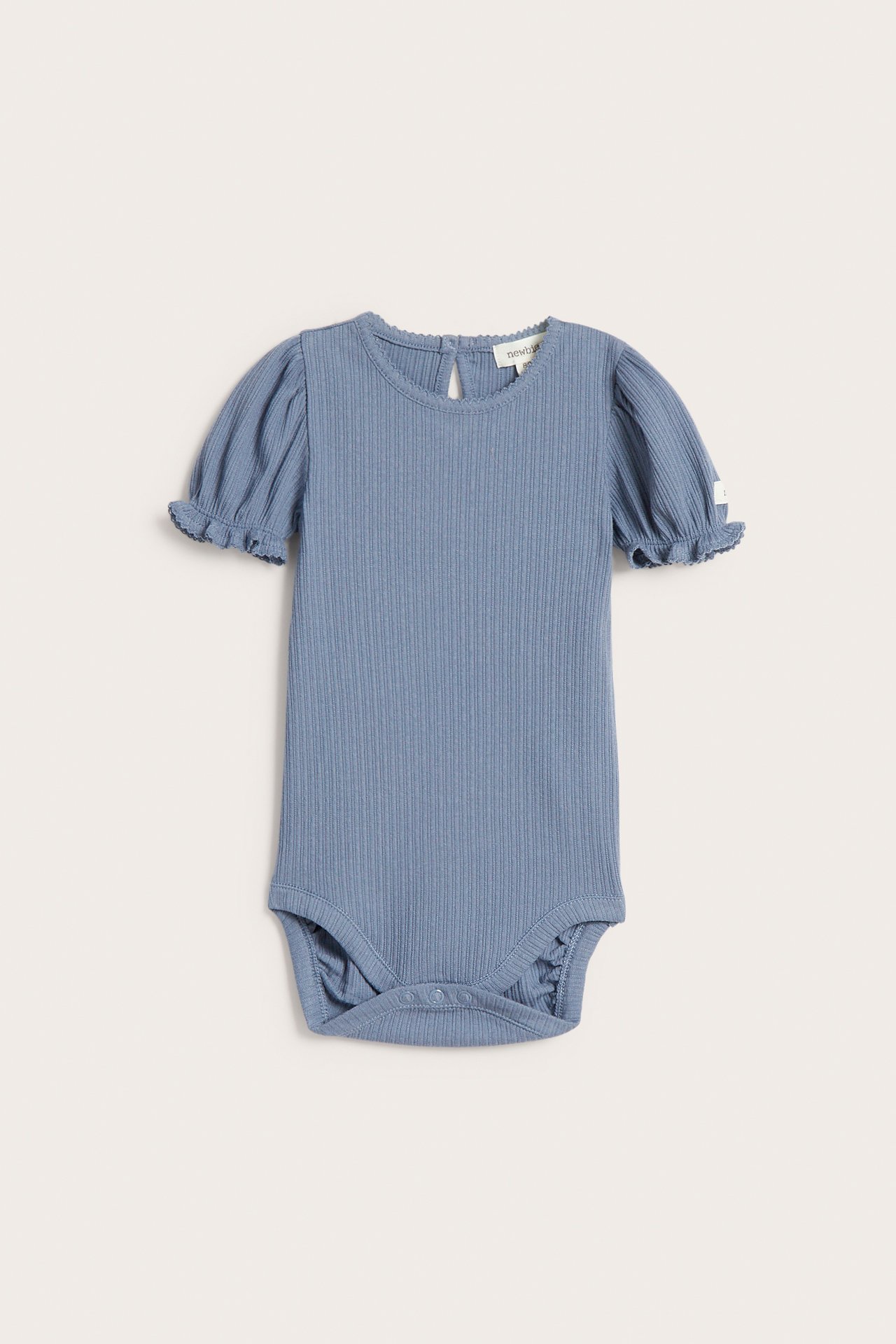 Front view of a solid blue ribbed jersey baby bodysuit with short puff sleeves, picot trim, and crotch snaps.