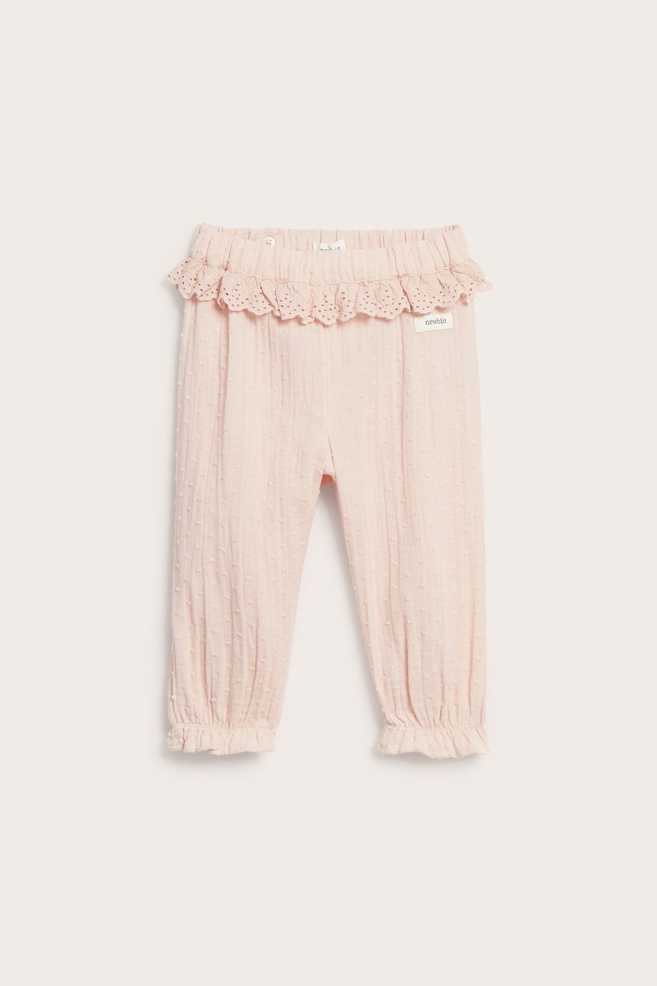 Vorderansicht: Hellrosa Kinder-Baumwollhose mit Punkttextur, Spitzenrüschenbund und Rüschen an den Beinbündchen.