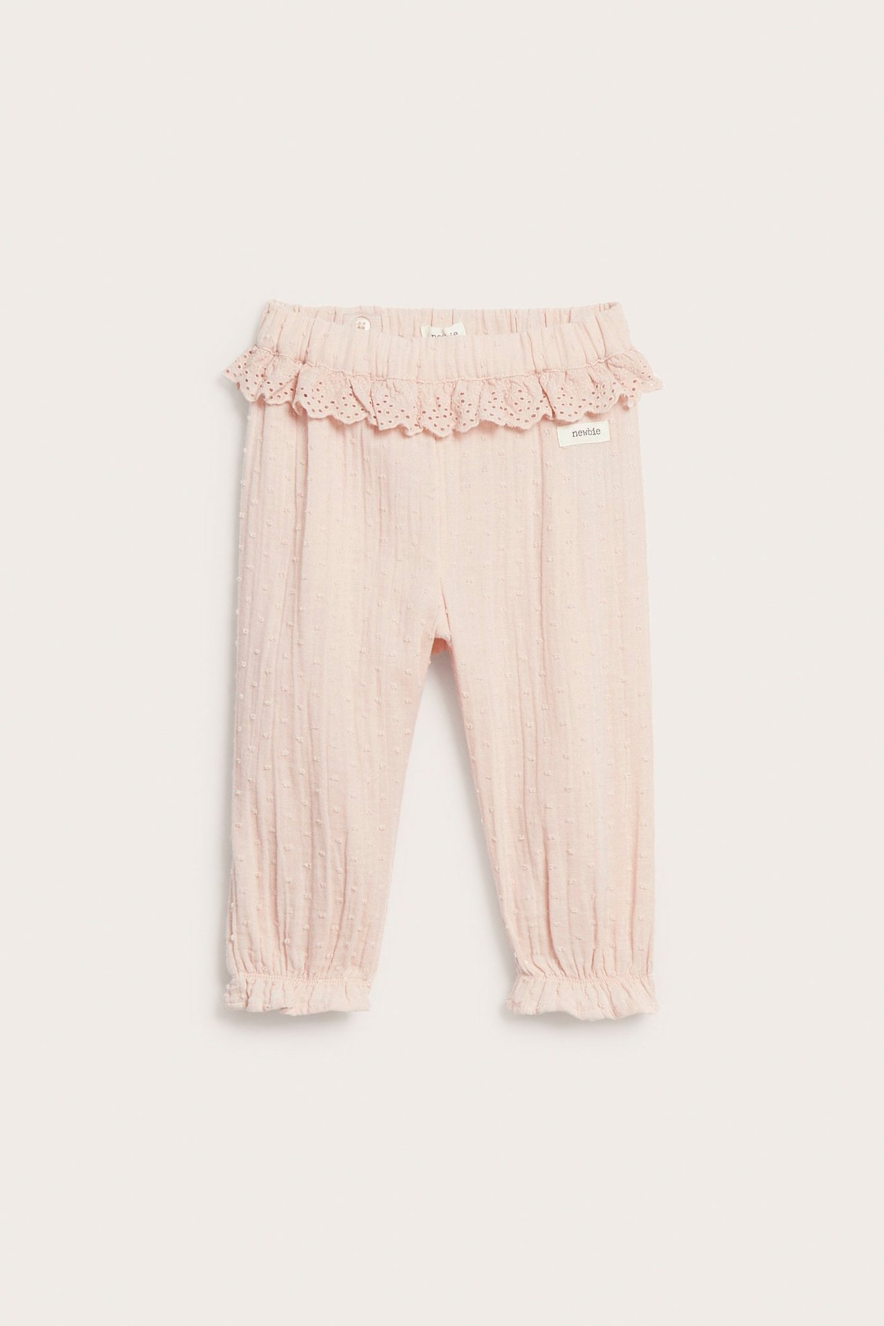 Vorderansicht: Hellrosa Kinder-Baumwollhose mit Punkttextur, Spitzenrüschenbund und Rüschen an den Beinbündchen.