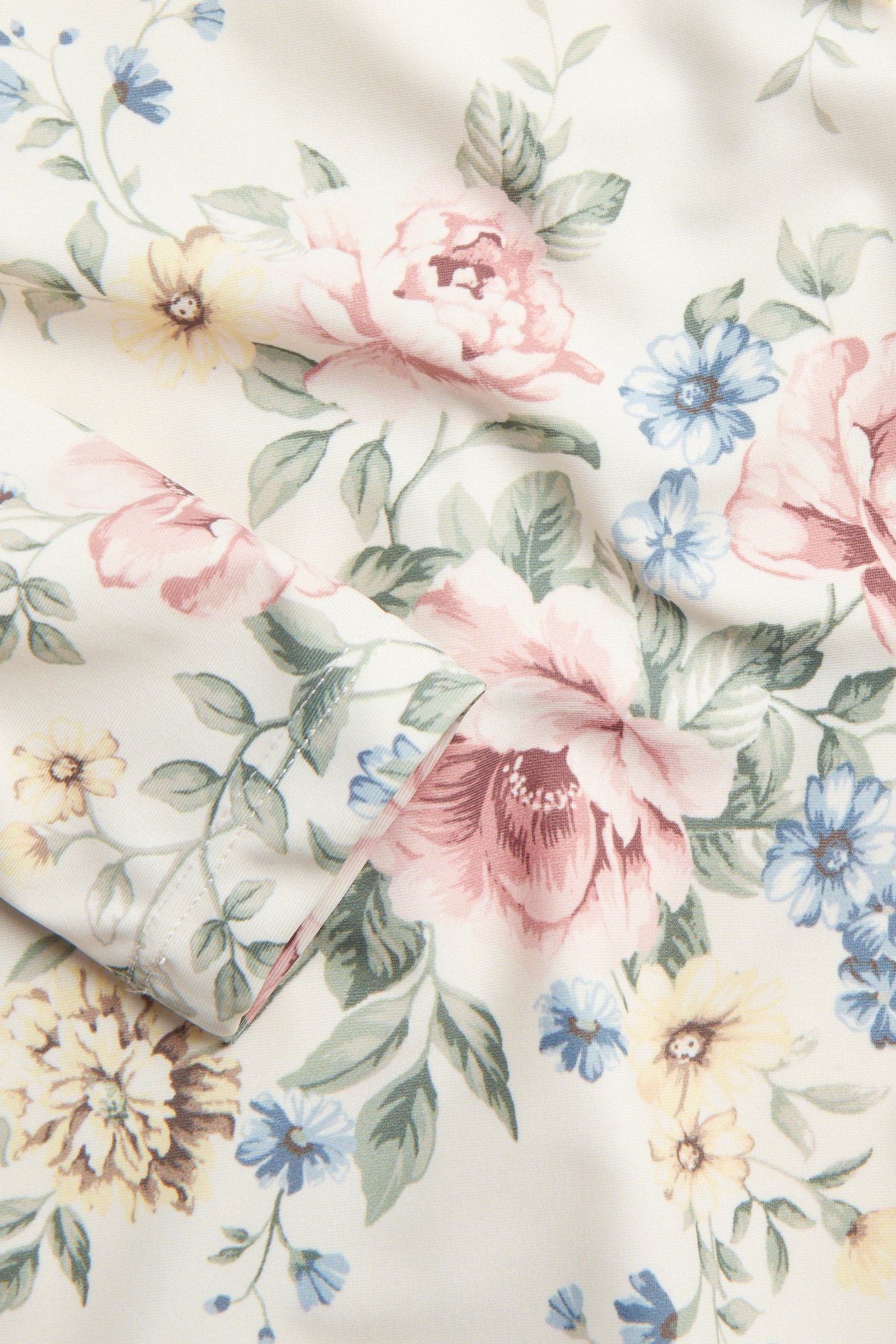 Nahaufnahme des cremeweißen UV-Oberteilstoffs mit detailliertem rosa, blauem und gelbem Blumenmuster.