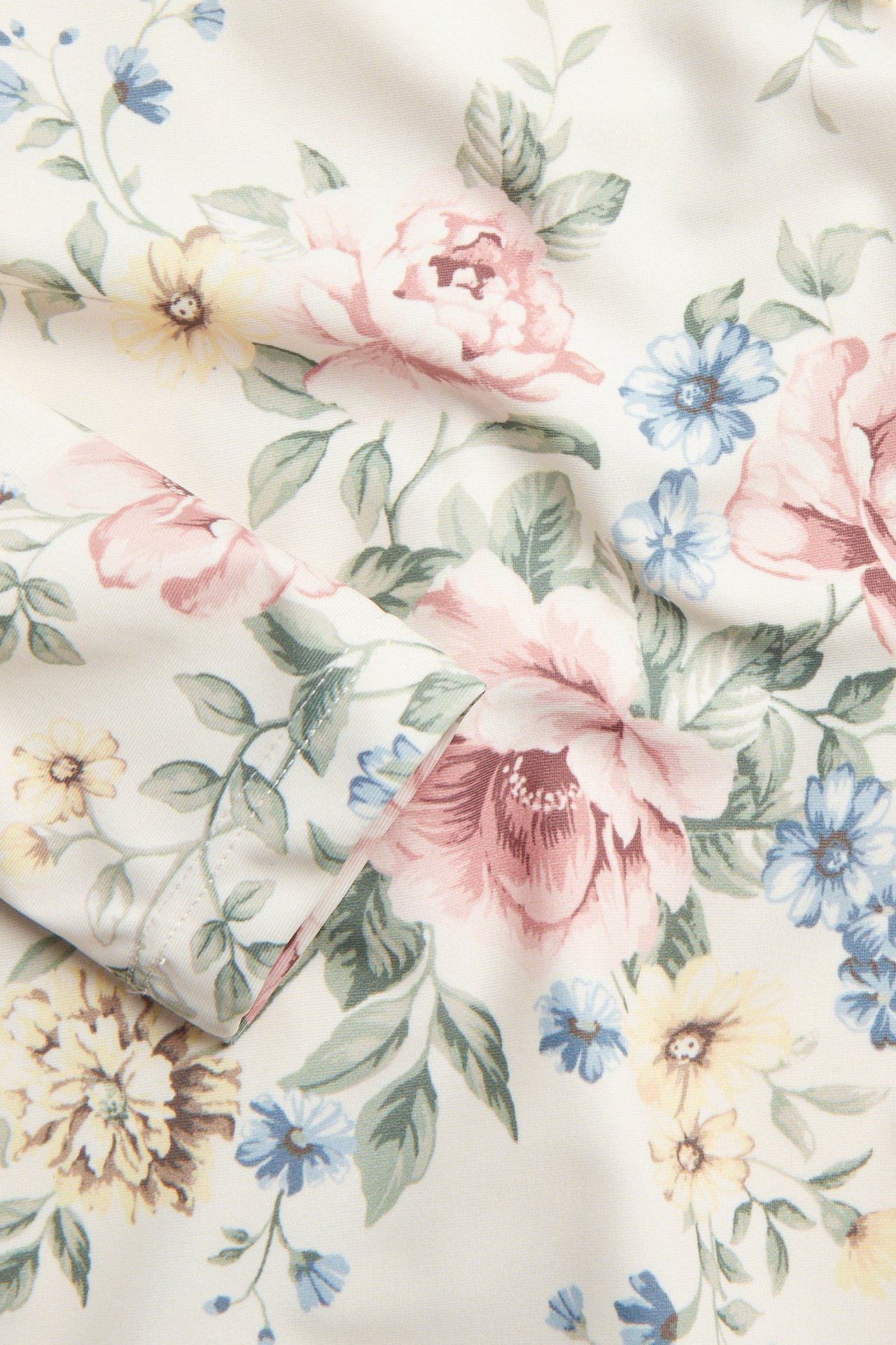 Nahaufnahme des cremeweißen UV-Oberteilstoffs mit detailliertem rosa, blauem und gelbem Blumenmuster.